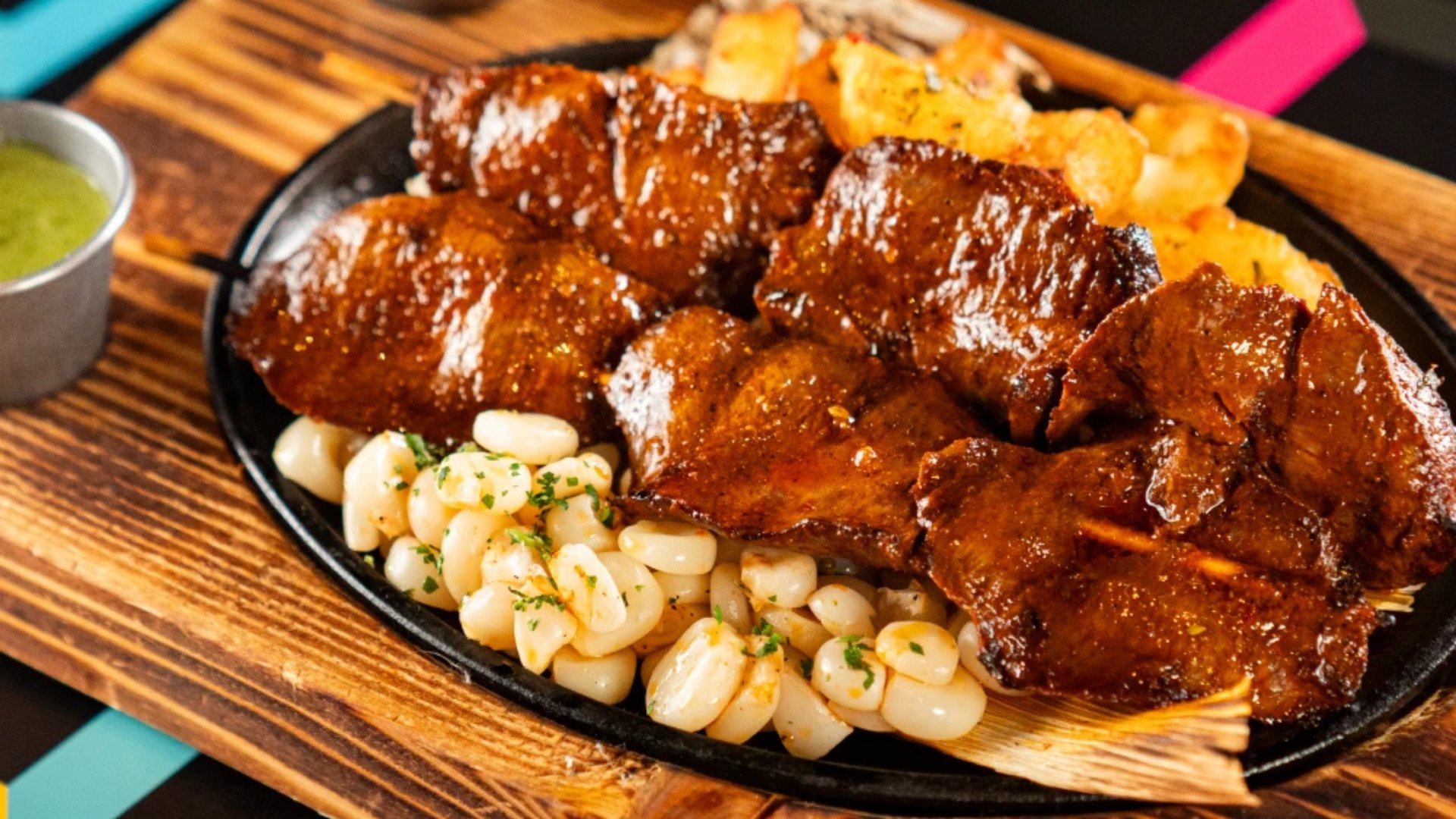 Grilled beef anticuchos skewers with white beans and aji verde sauce on cast iron skillet