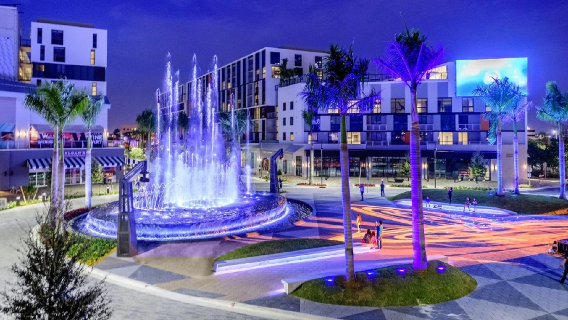 CityPlace Doral Holiday Market illuminated fountain with blue light display and palm trees at twilight featured by The Edit Real Estate