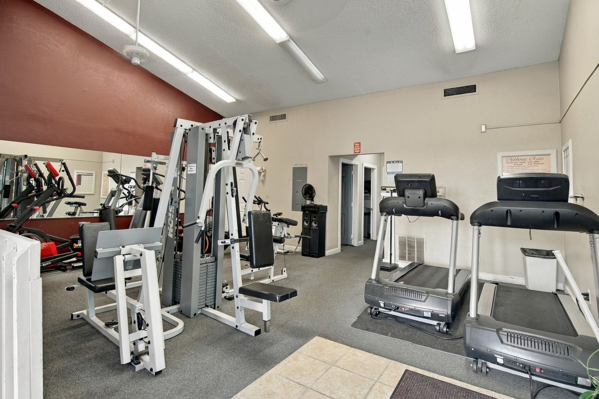 Fitness room with weight machines, exercise bikes, two treadmills, and a mirrored wall.