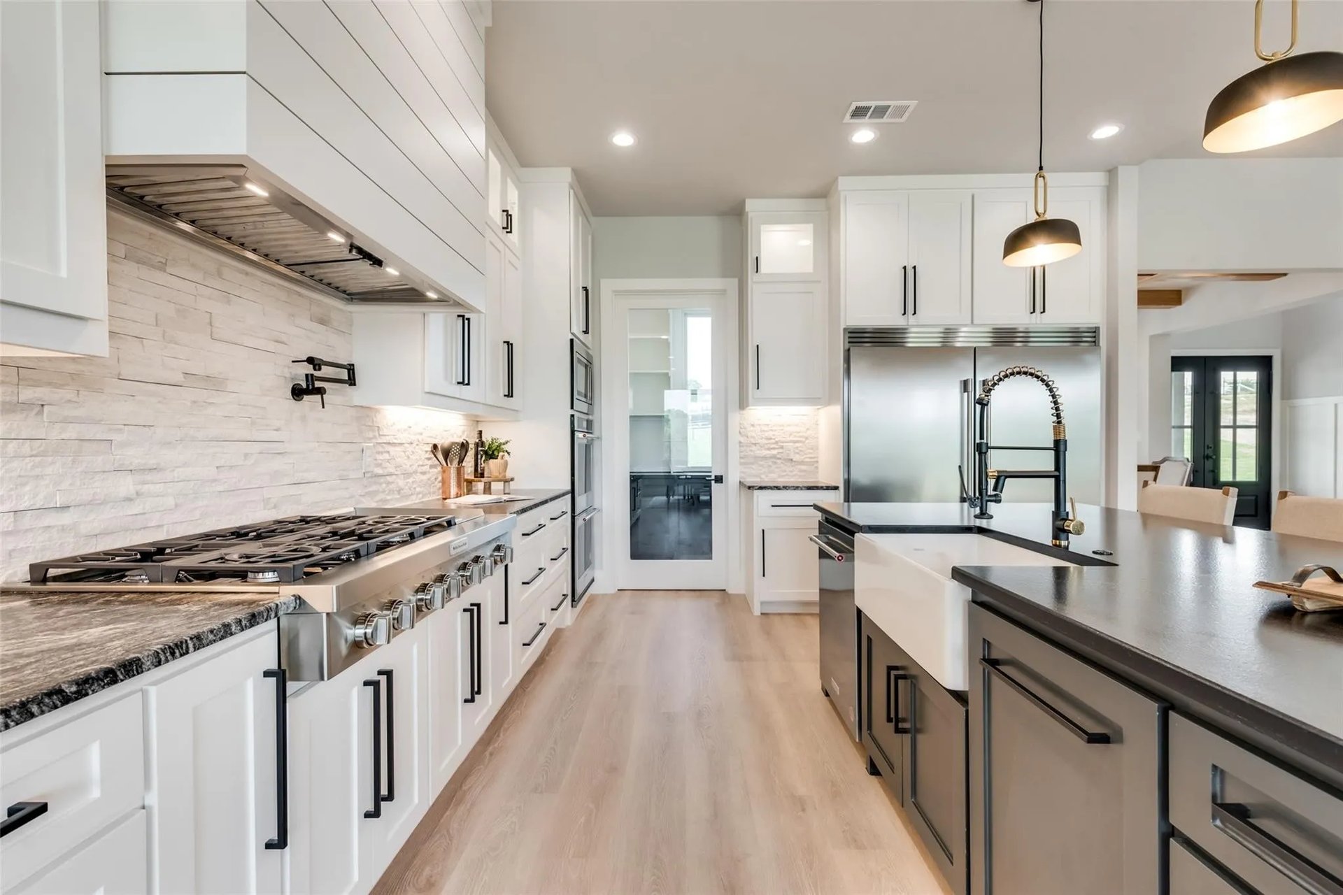 Modern kitchen with white cabinetry, a large dark-countertop island, and stainless steel range.