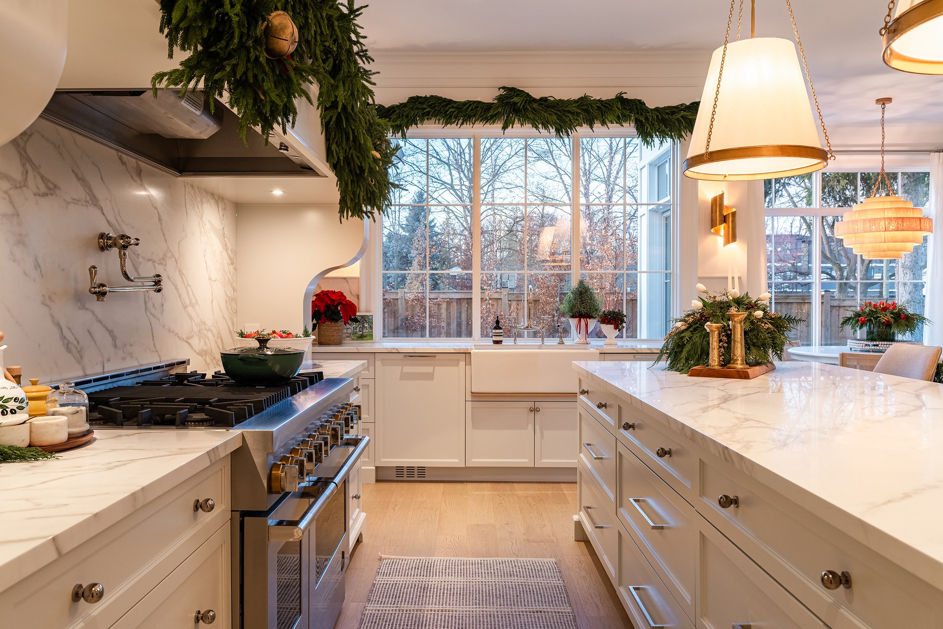 Marble kitchen in an Oakville custom home with farmhouse sink, greenery garland across hood and windows, and holiday d&eacute;cor accents.