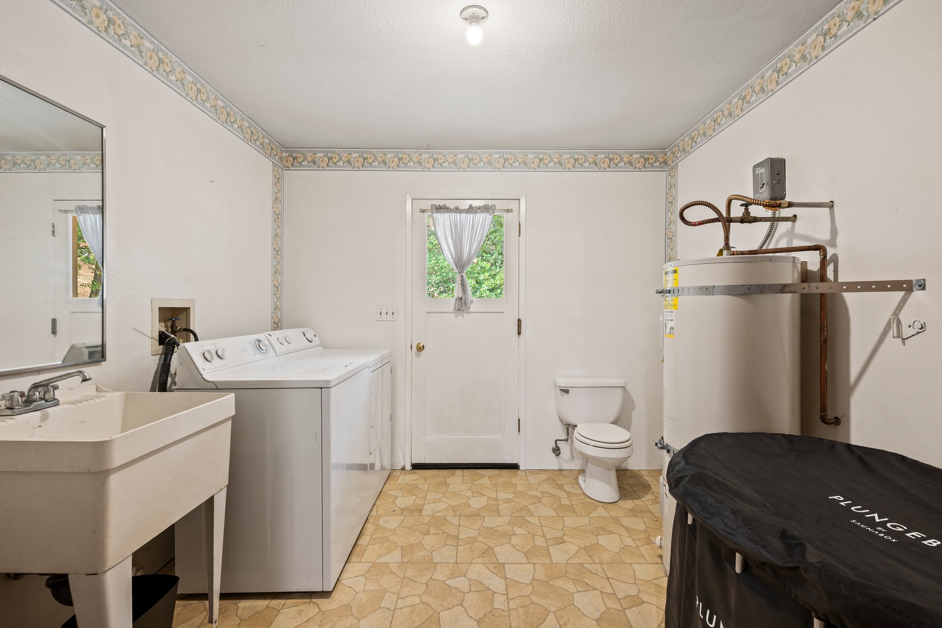 Laundry room with washer and dryer, utility sink, toilet, and water heater.