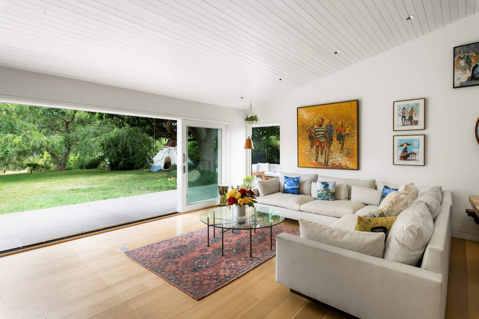 Living room with a white sectional and sliding glass doors opening to a leafy lawn.