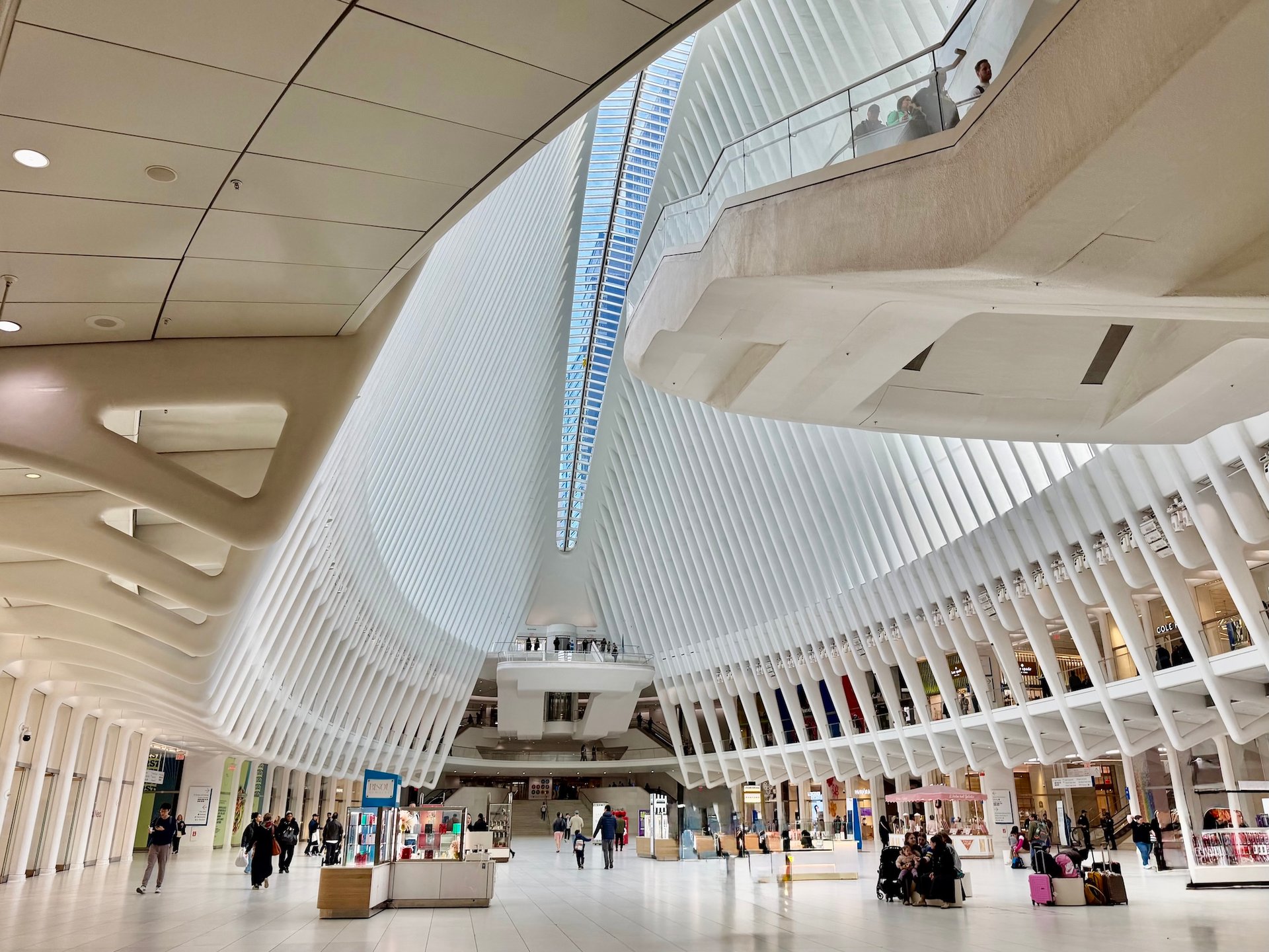 The Oculus interior, with sweeping white ribs, upper walkways, and shoppers below.