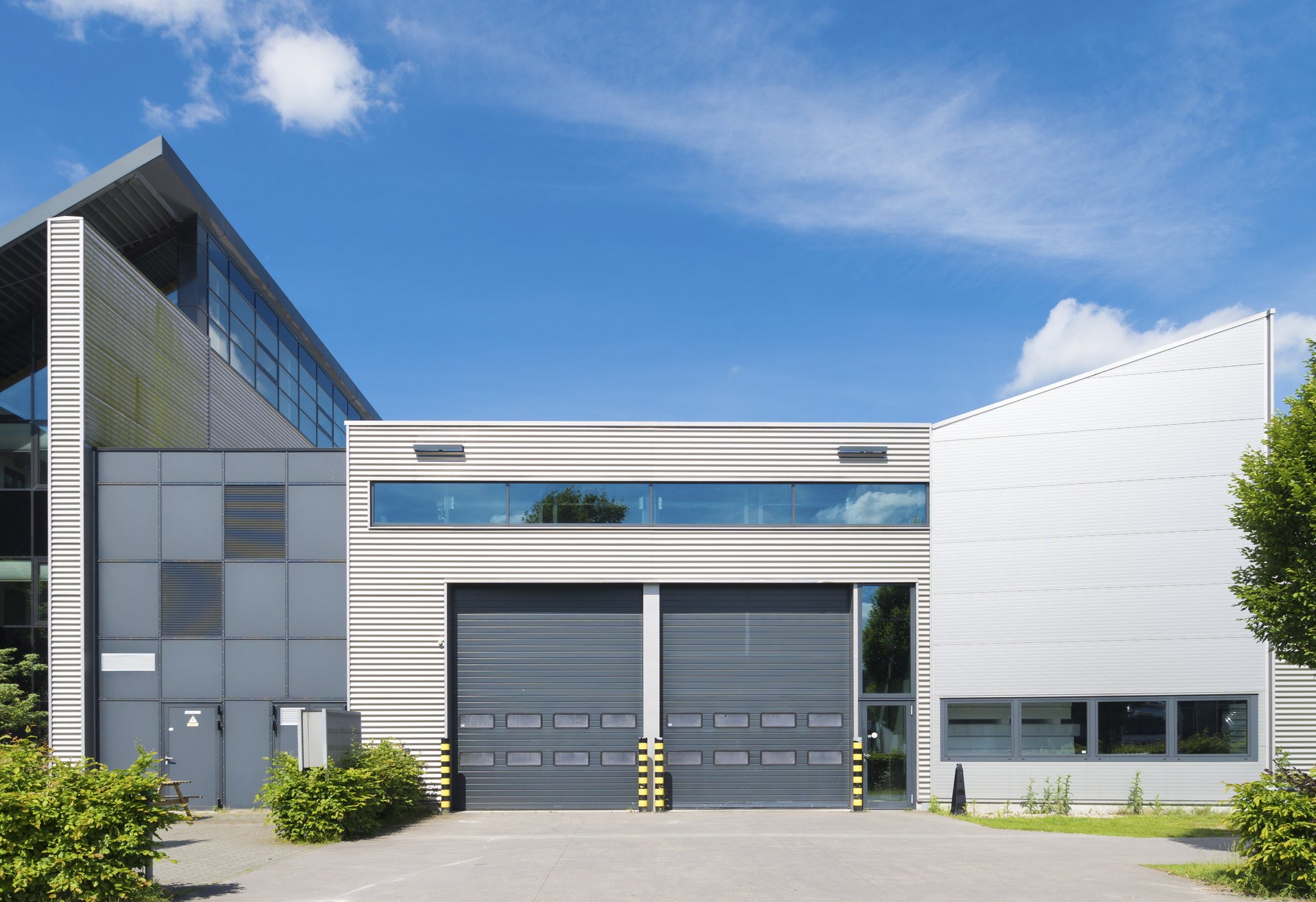 Modern industrial warehouse with two large loading doors and horizontal windows.