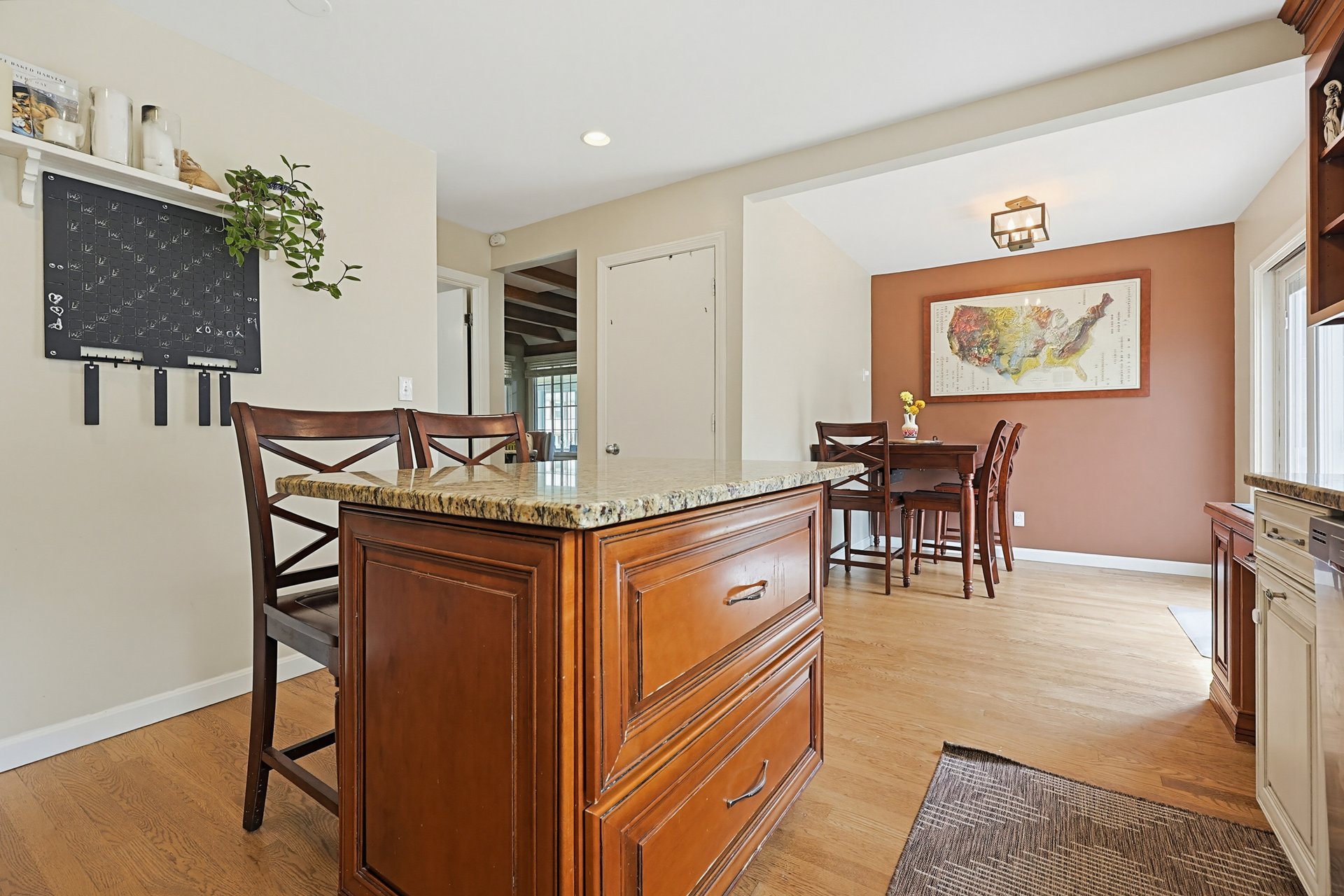 Kitchen and dining area with a large wood island, stone countertop, and terracotta accent wall.