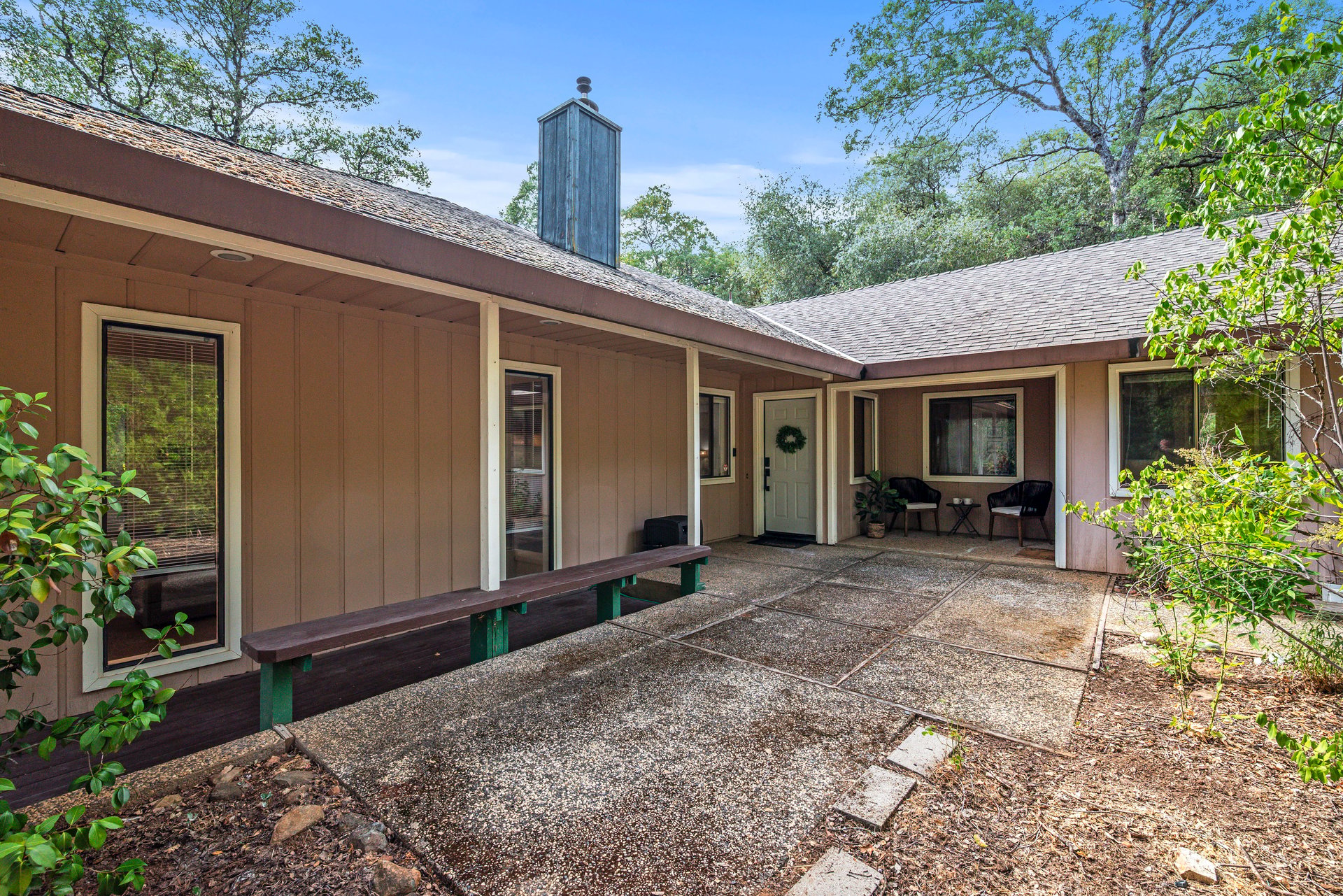 Home courtyard with a covered entry, built-in bench, and two outdoor chairs.