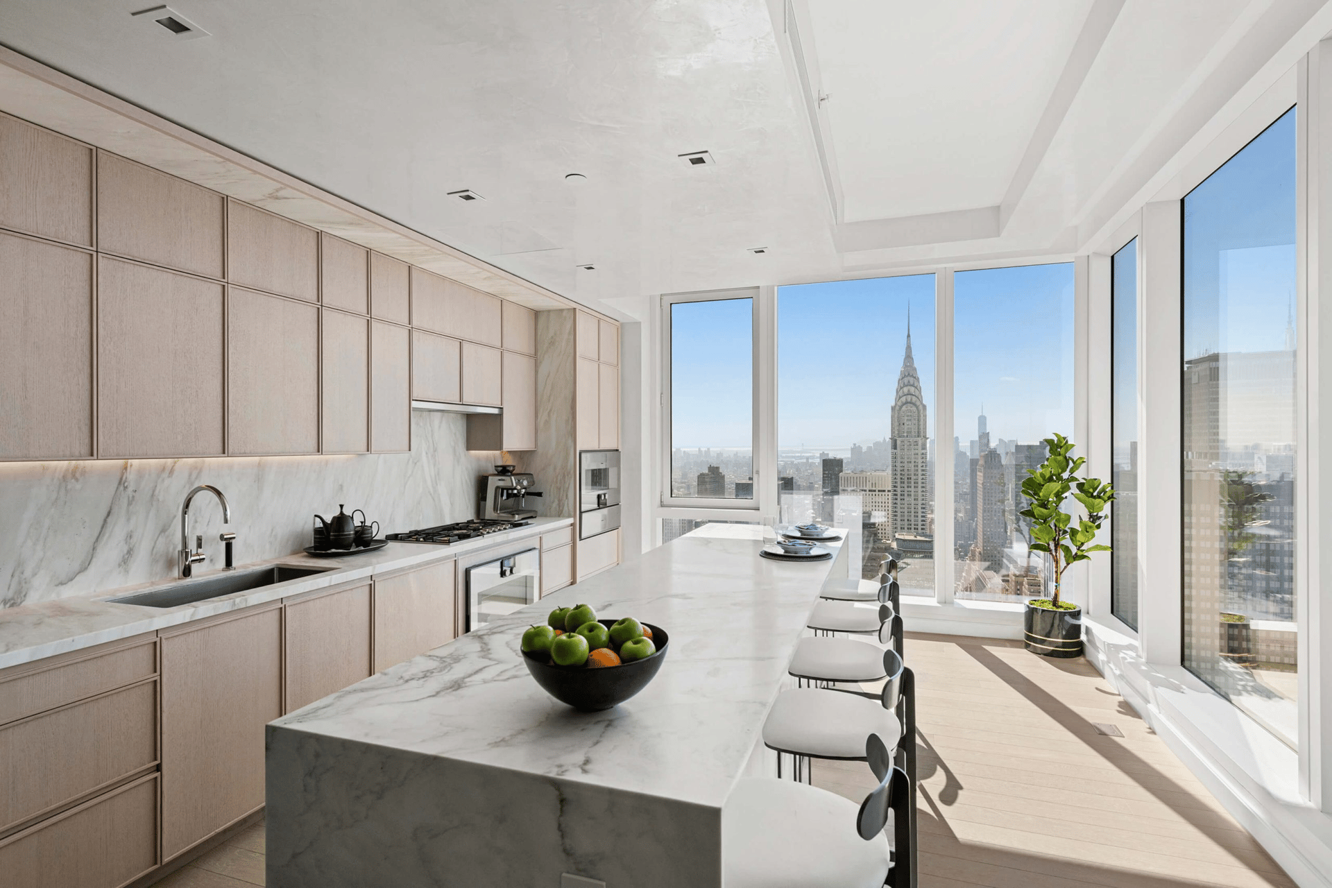 Bright modern kitchen with a marble island and floor-to-ceiling windows overlooking the Chrysler Building.