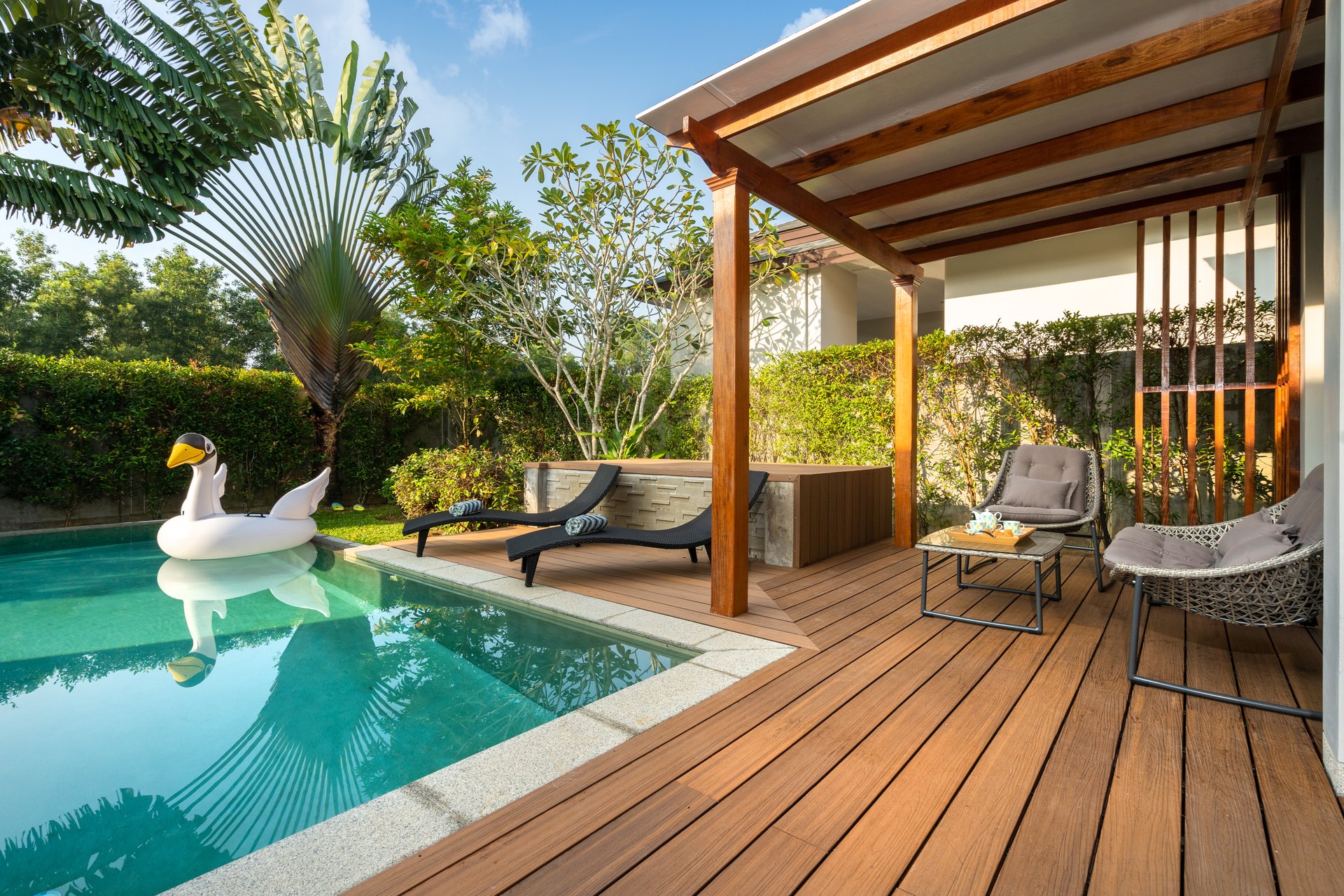 Relax by the poolside at a tropical-style Aspen vacation home rental with cozy loungers and lush greenery.