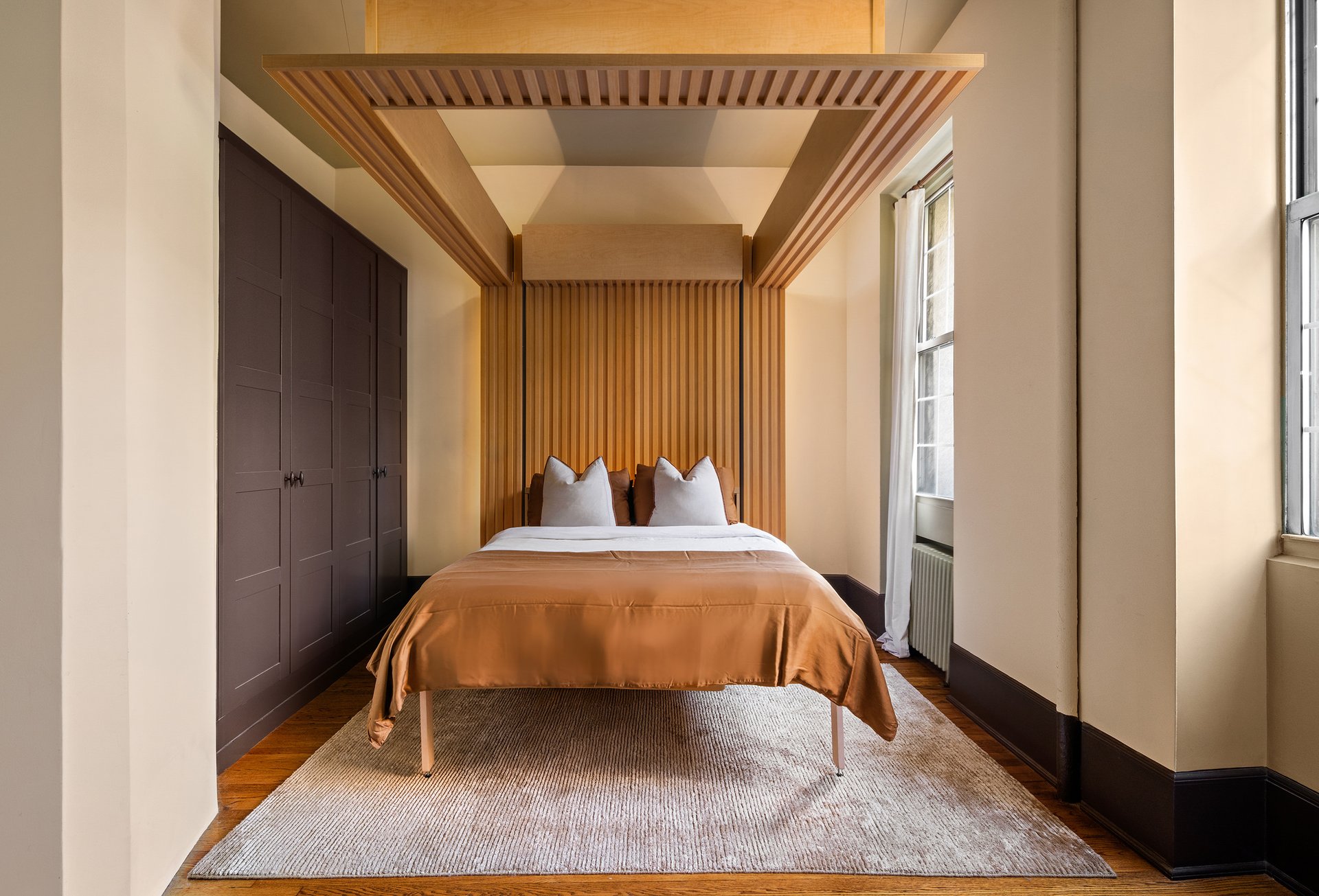 Bed lowered in the same alcove at 207 West 21st Street, 3F, framed by wood slats and built-in cabinets.