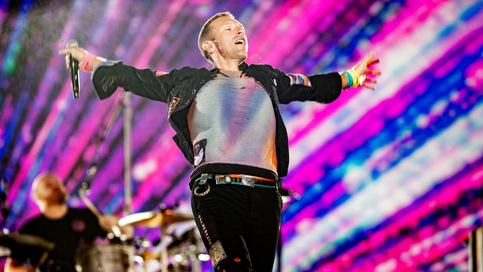 The Edit Real Estate Miami guide showcasing concert magic with performer on stage under colorful pink and blue lighting effects