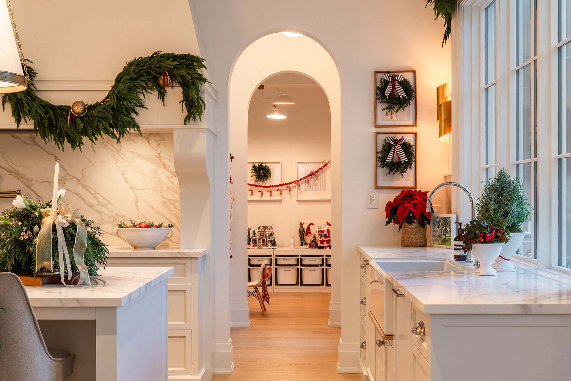 Farmhouse sink area in an Oakville custom home styled with poinsettias, greenery, brass accents, and festive holiday d&eacute;cor.
