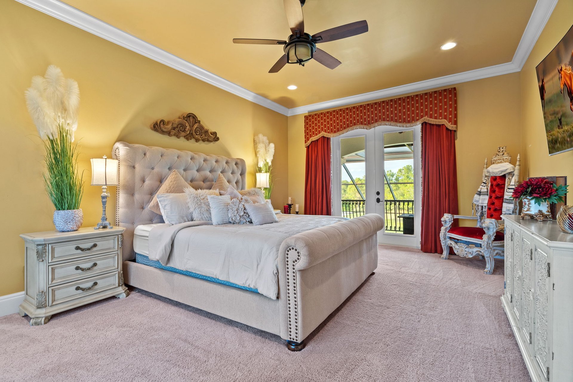 Furnished bedroom with a tufted bed, red curtains, and glass doors opening to a balcony.