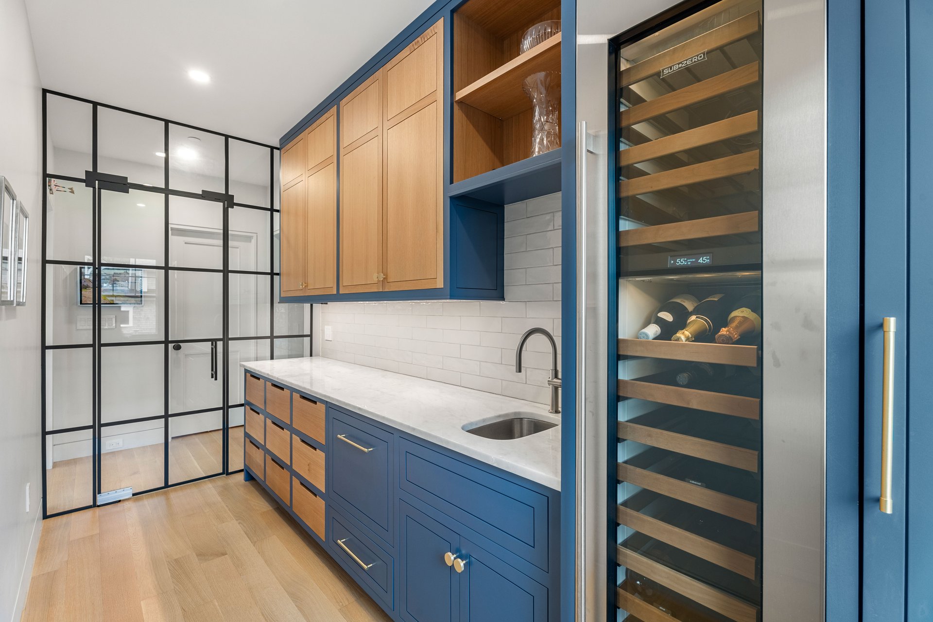 Kitchen pantry with navy and wood cabinetry, a glass partition, and a built-in wine refrigerator.