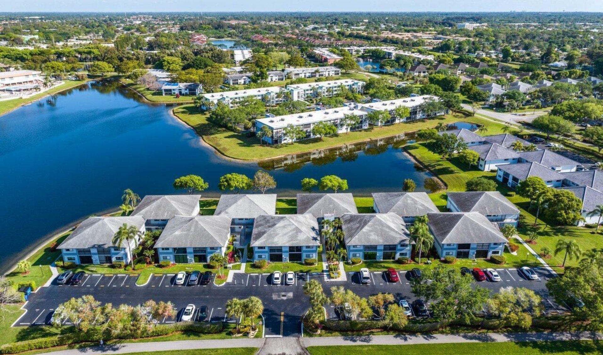 Aerial view of low-rise homes and condominiums bordering a large lake.