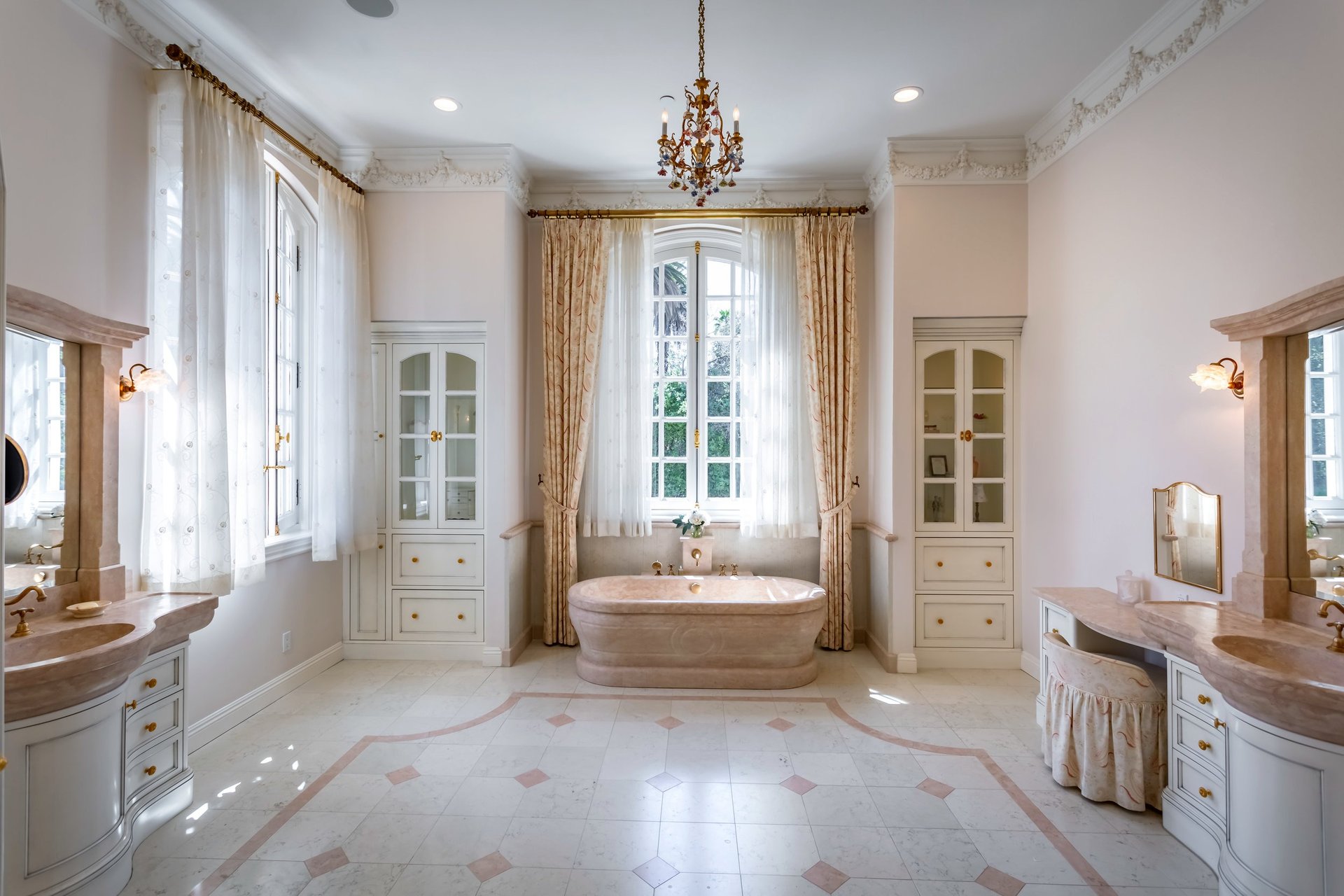 French-style bathroom with a freestanding marble tub, arched window, and matching vanities.