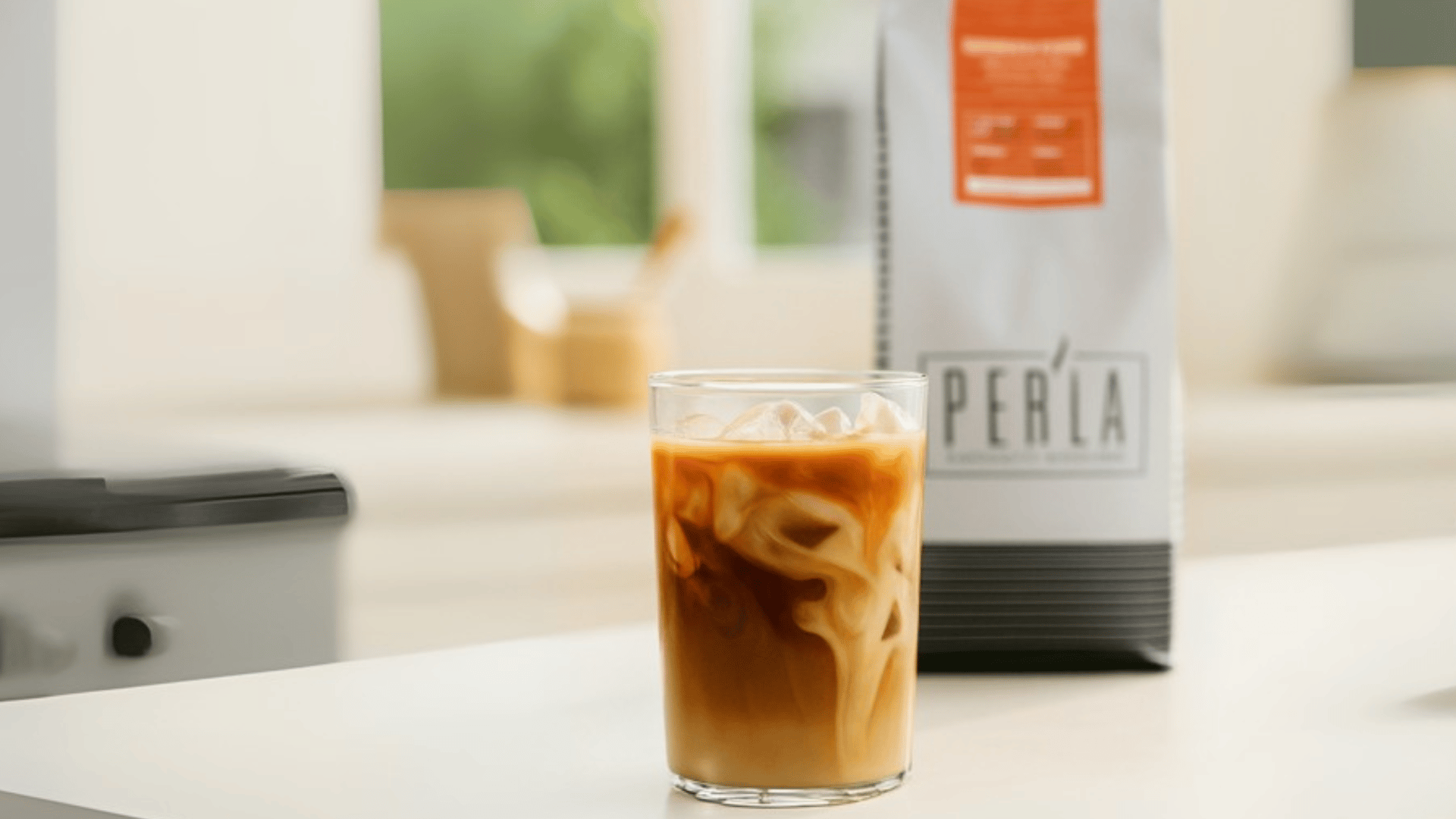 Peria iced coffee with cream swirl in glass on modern white counter - Miami specialty coffee shop by The Edit Real Estate