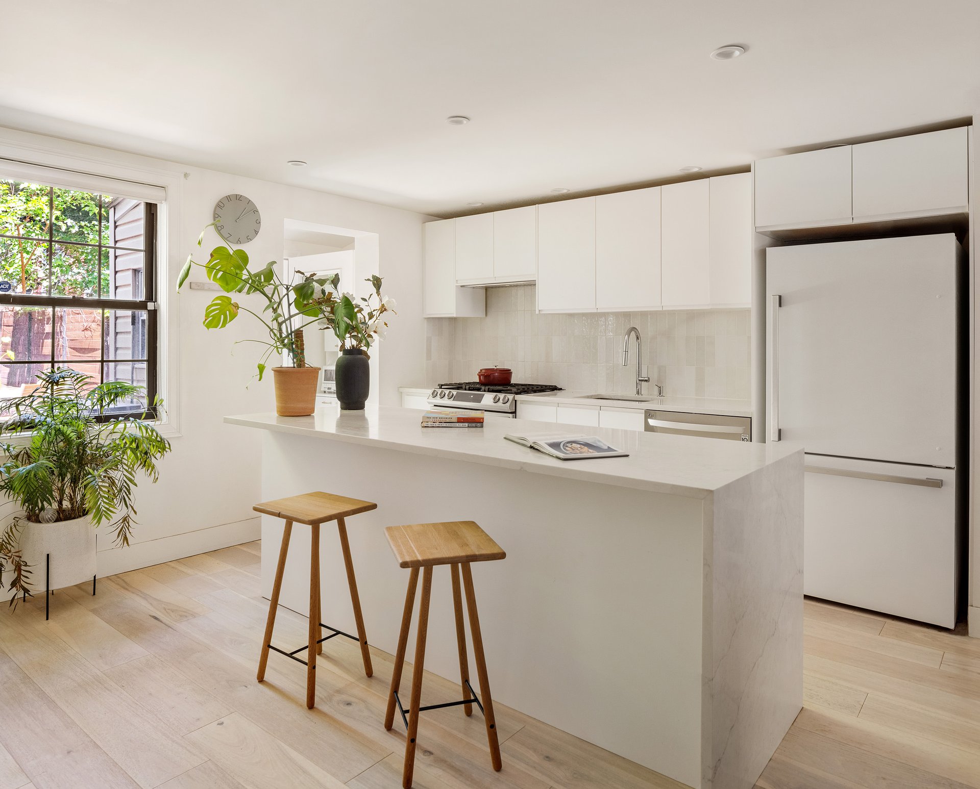 Kitchen at 457 Lexington Avenue with white cabinets, an island and two stools.
