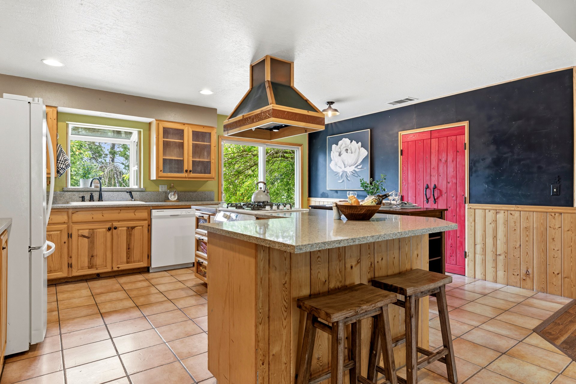 Kitchen with wood cabinets, a large granite island, and a distinctive red pantry door.