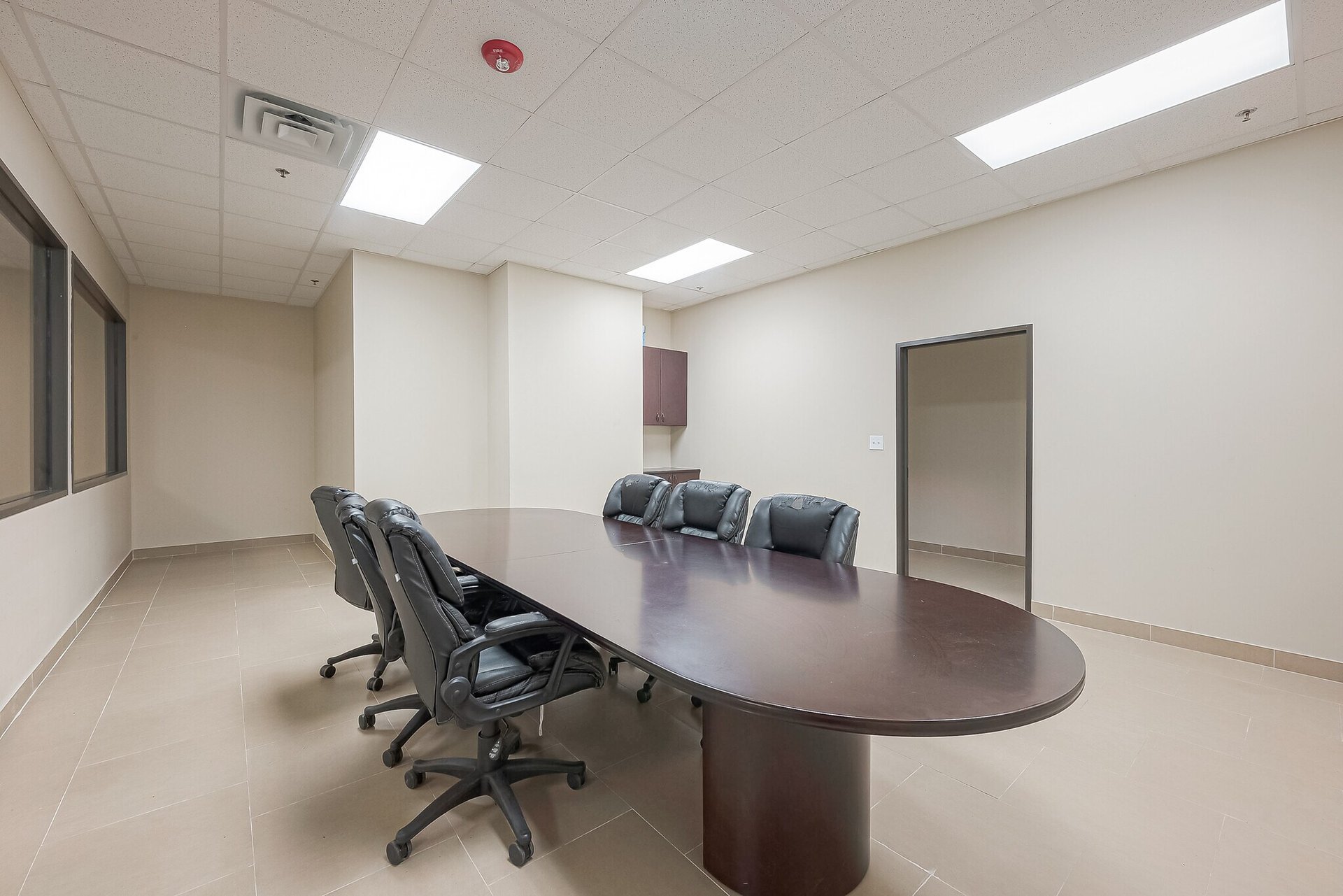 Office conference room with a long oval table and black rolling chairs.