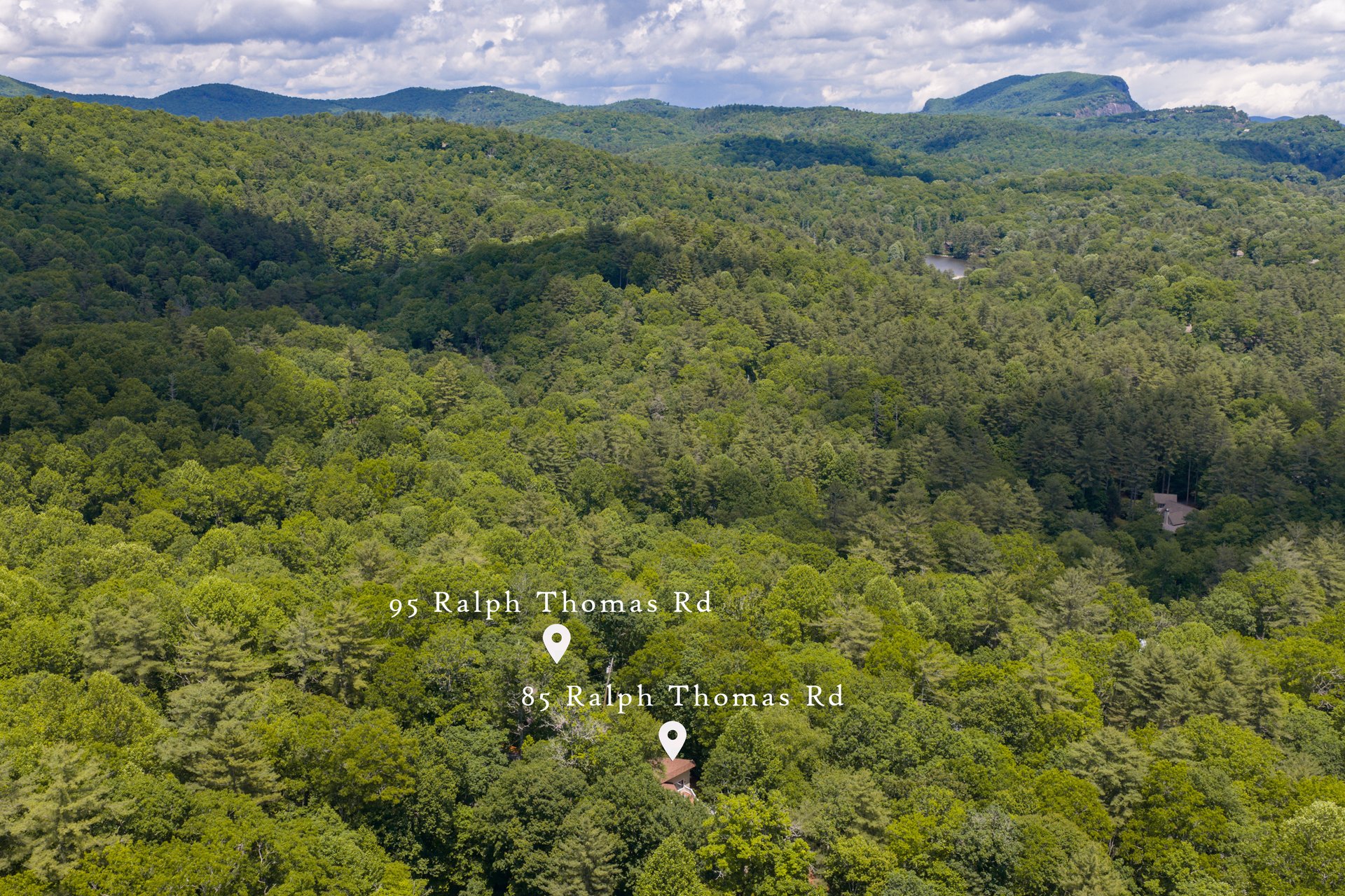 Aerial view of 85 and 95 Ralph Thomas Rd in Highlands NC, surrounded by forest with mountain ridges in the distance