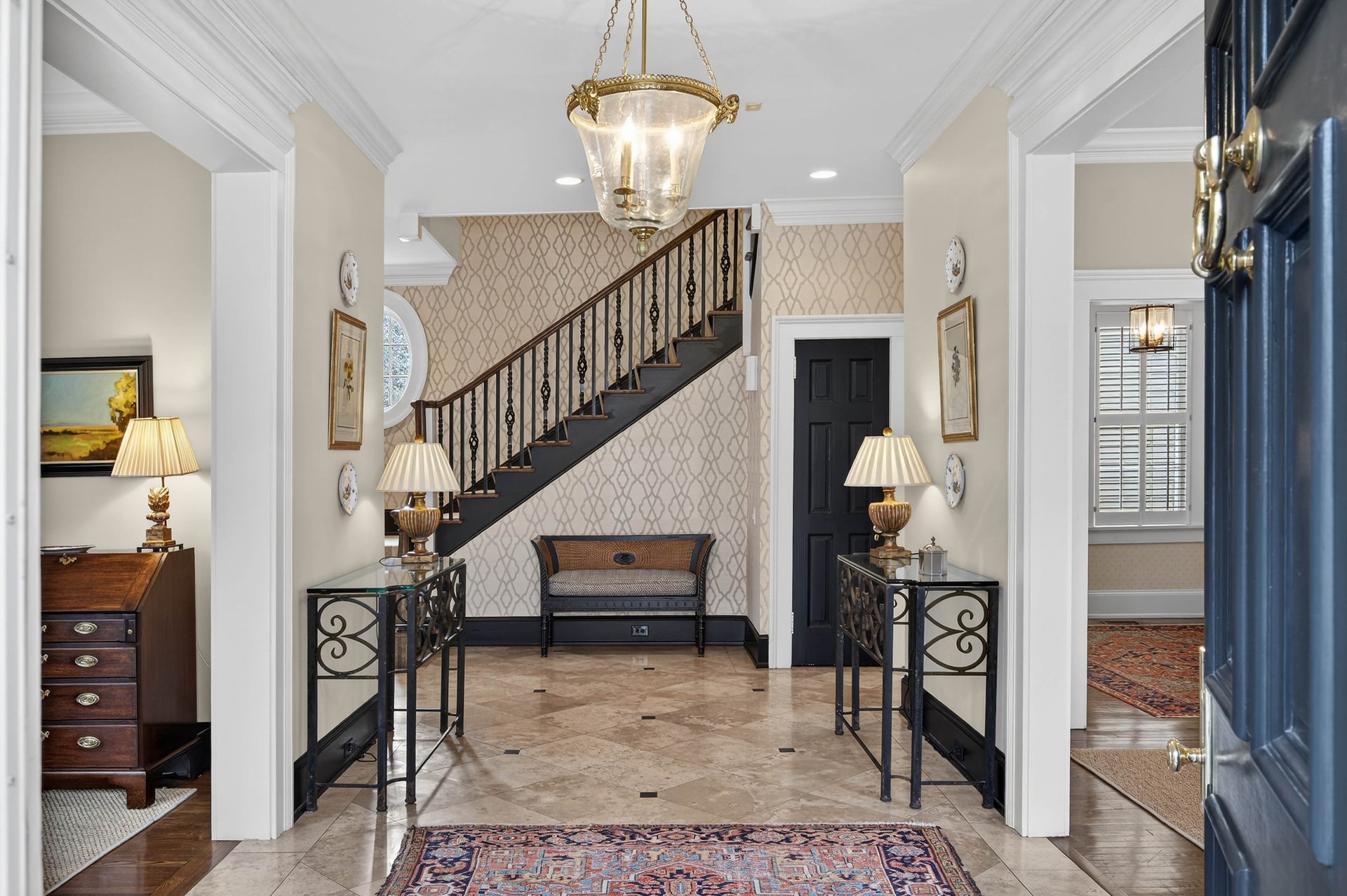 Traditional luxury home foyer in Buckhead with staircase, lantern chandelier, marble tile floors, and classic console tables.