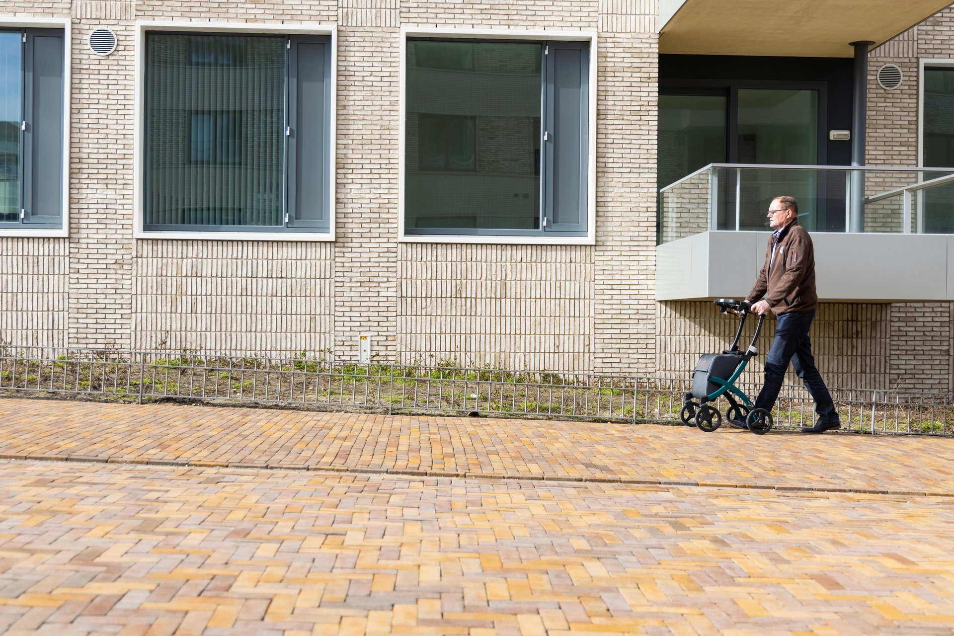  Older adult using a mobility aid along a residential walkway