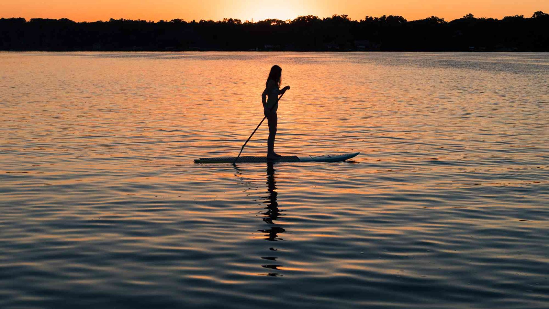 Woman paddleboarding at sunrise near Kiawah Island, embracing coastal Lowcountry lifestyle