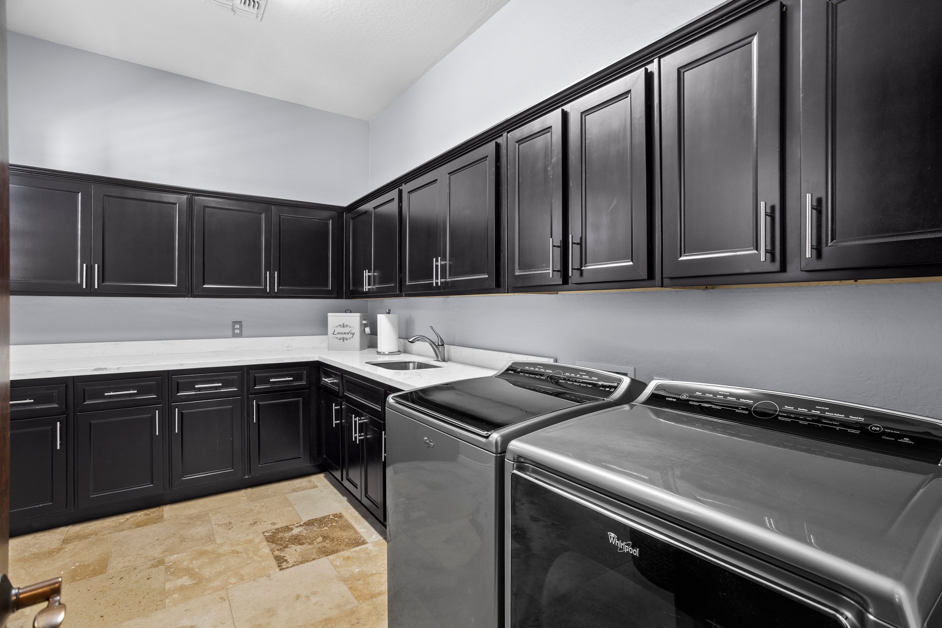 Laundry room with dark cabinets, white countertop, utility sink, and washer and dryer.