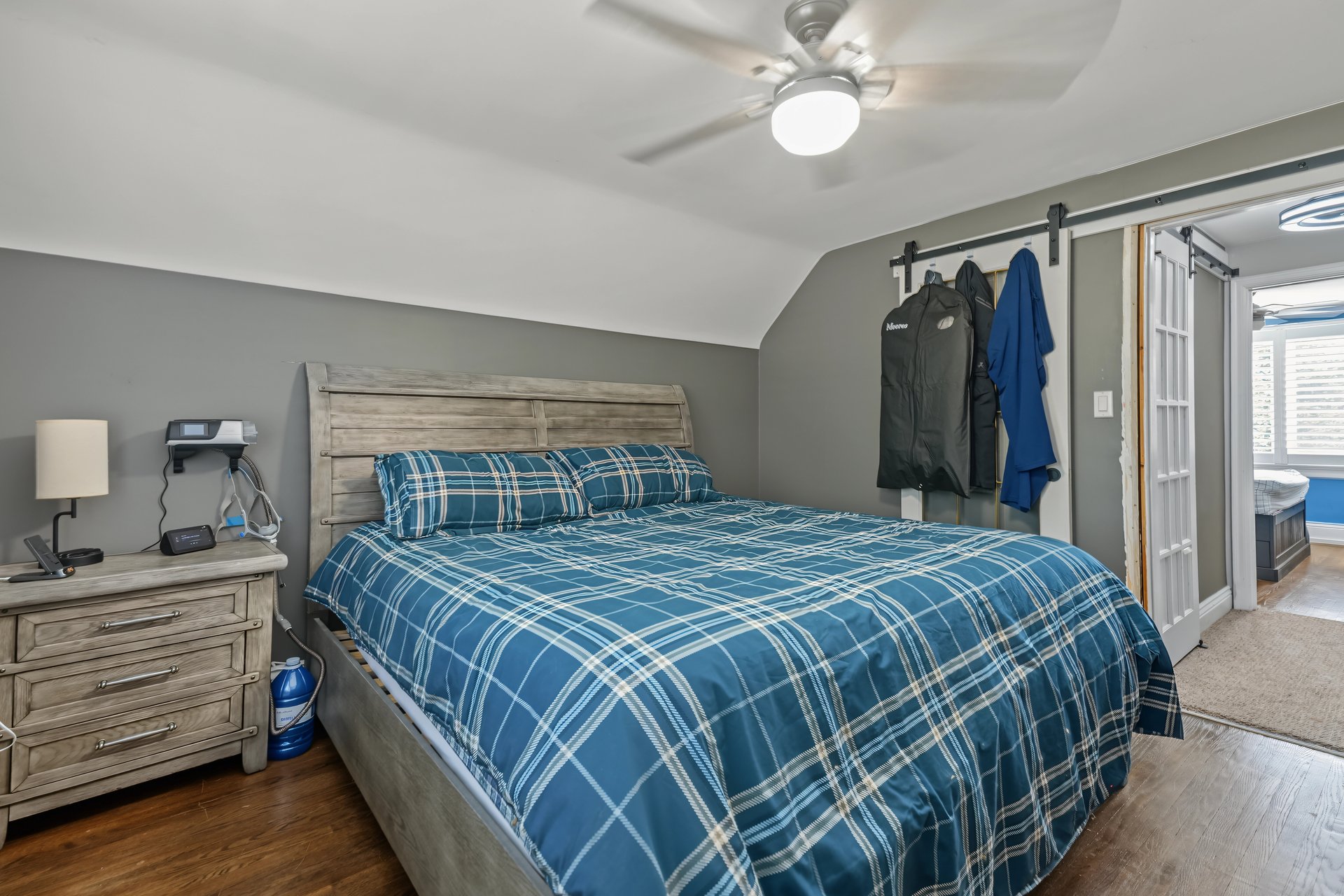 Bedroom with blue plaid bedding, weathered wood furniture, and a ceiling fan.