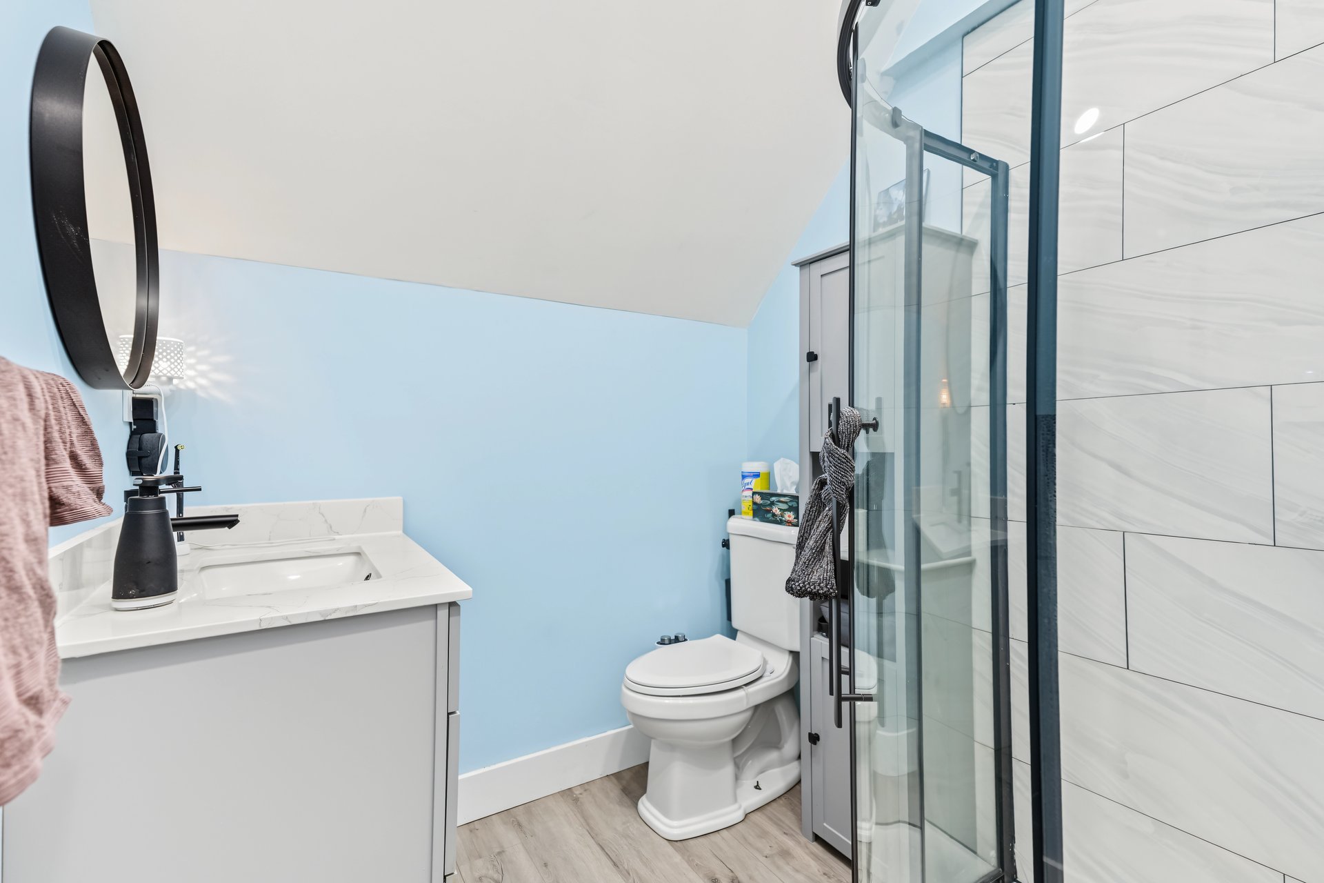 Bathroom with blue walls, a white vanity, and a glass-enclosed tiled shower.