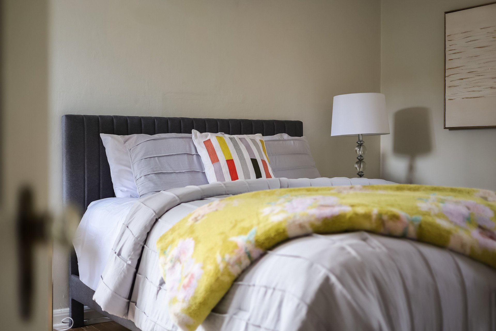 Bedroom with a dark upholstered headboard, white bedding, and a yellow floral throw.