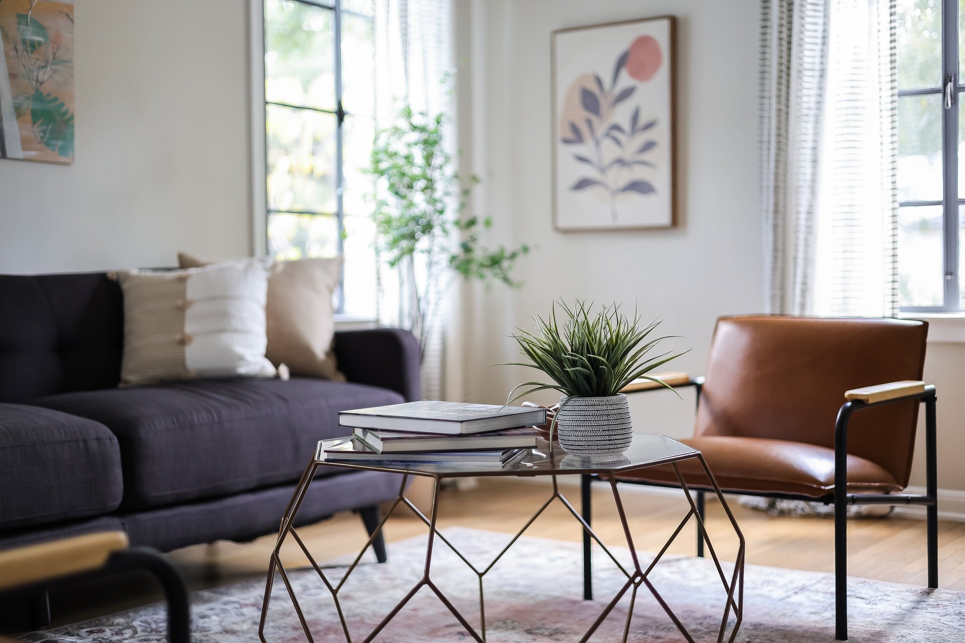 Staged living room with a charcoal sofa, leather armchair, and glass coffee table.