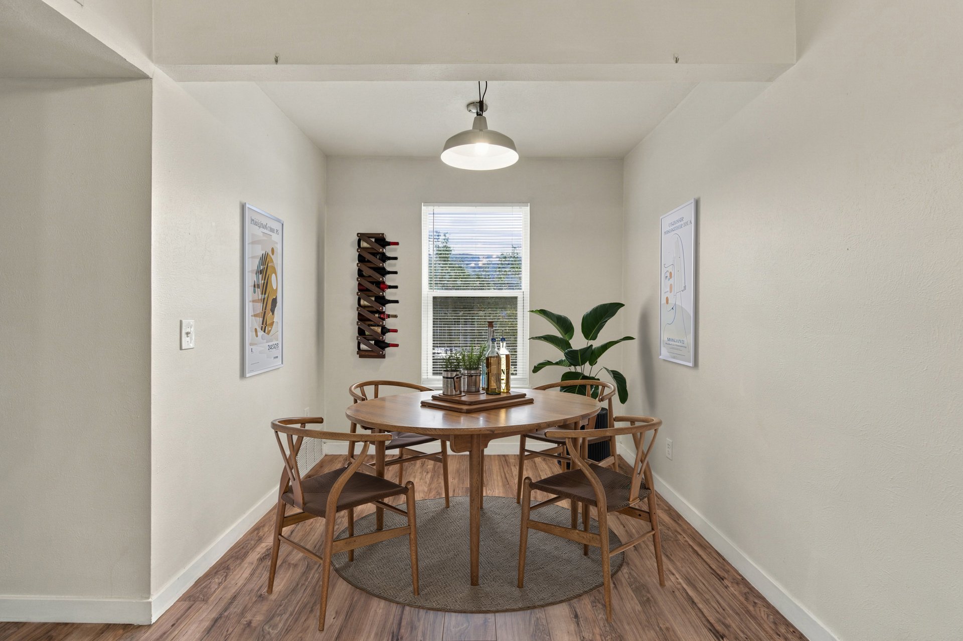 Dining area with a round wooden table, four chairs, and a window with blinds.