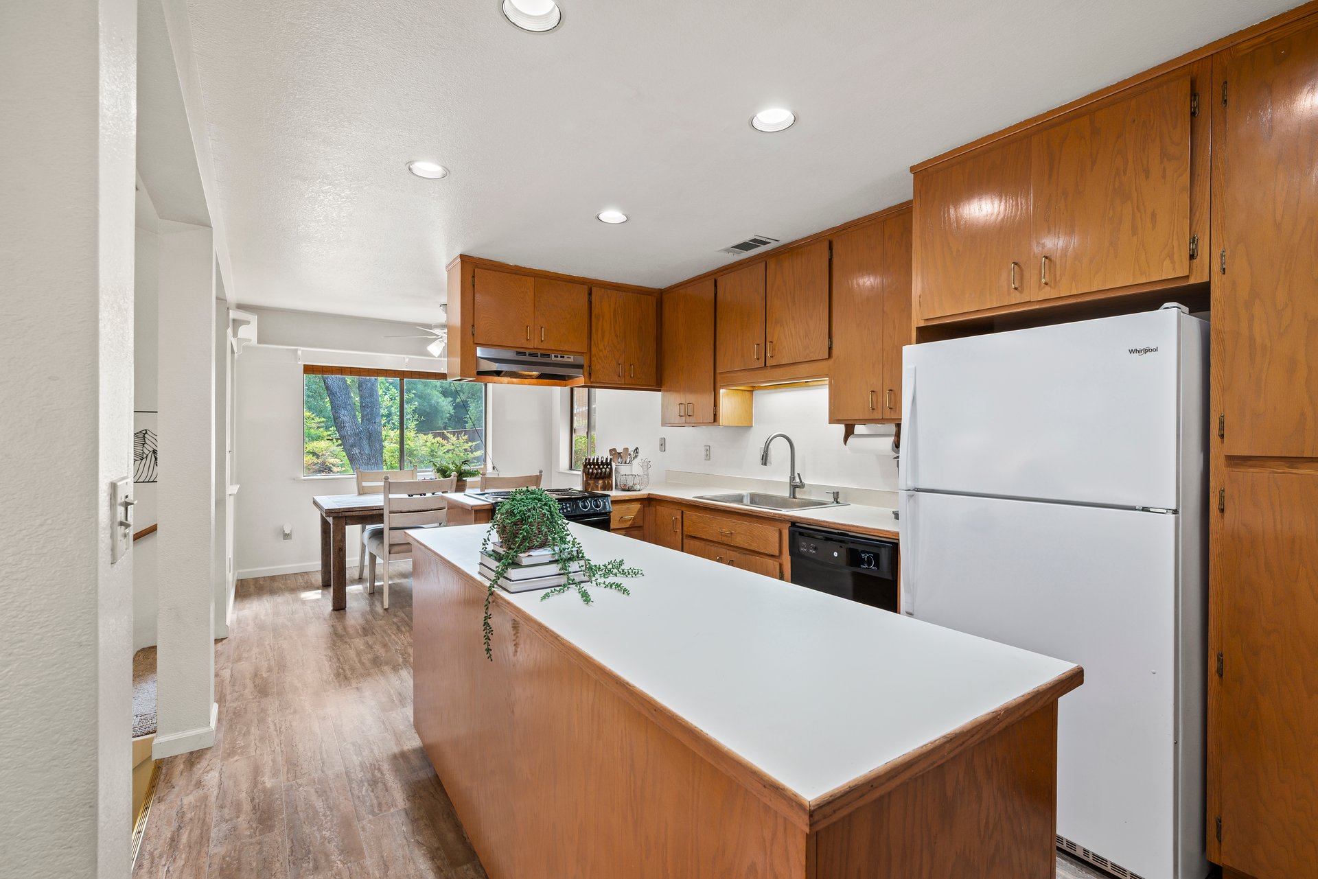 Kitchen with wood cabinets, a large white island, and an adjoining dining area by the window.