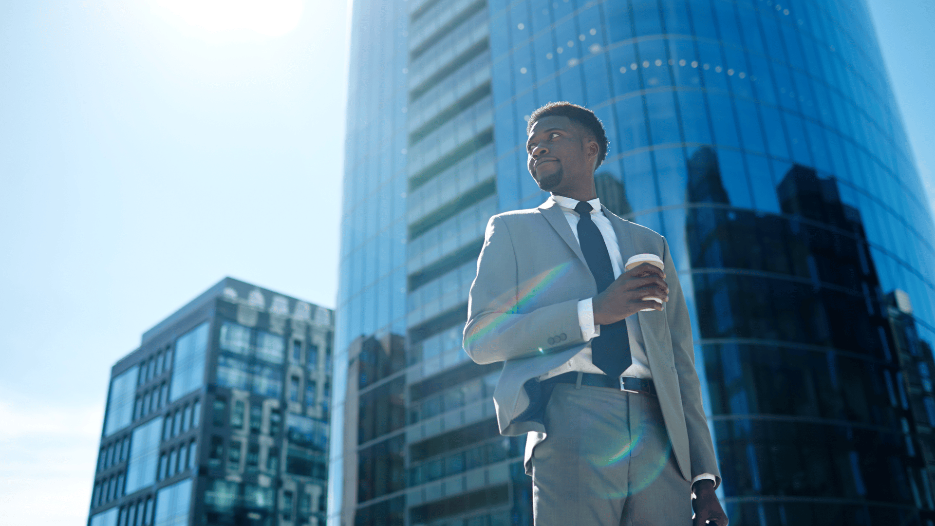 Business executive standing in front of modern Miami commercial building - corporate relocation services by The Edit Real Estate Miami