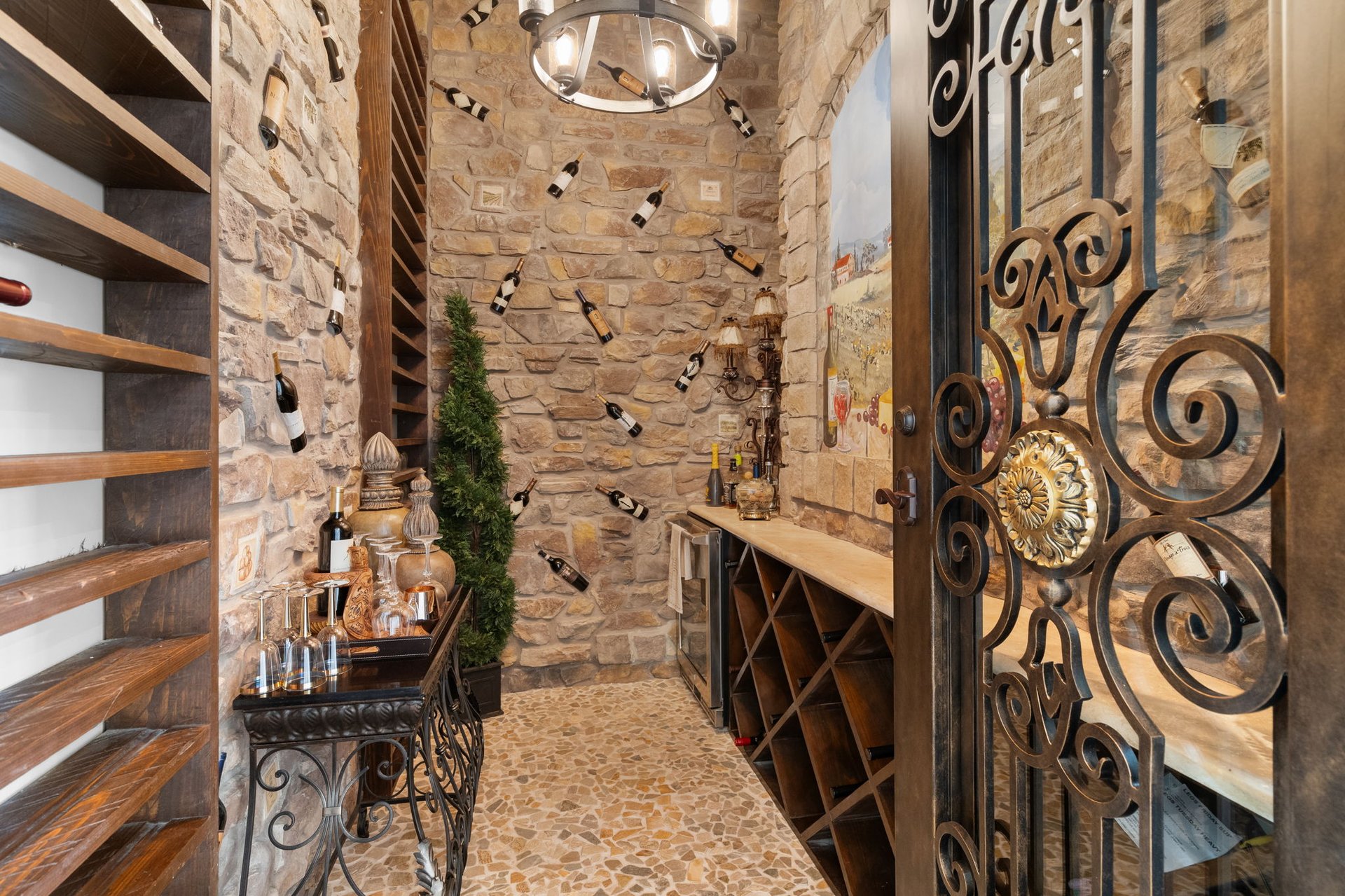 Wine cellar with stone walls, wooden wine racks, and an ornate wrought-iron gate.