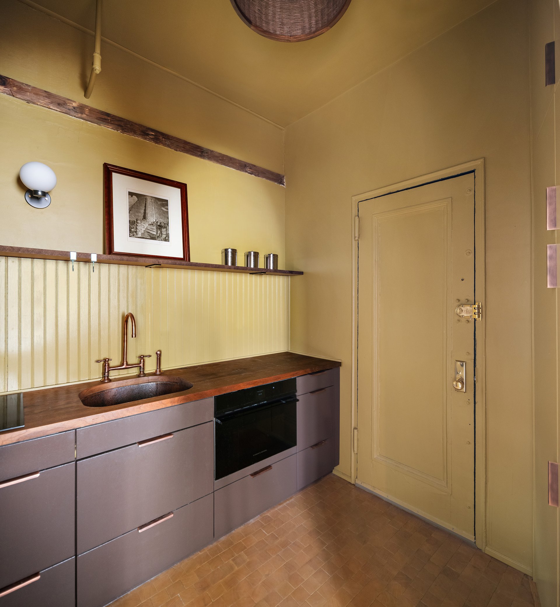 Kitchen with a wood countertop, copper-toned sink and faucet, flat cabinet fronts and a paneled backsplash.