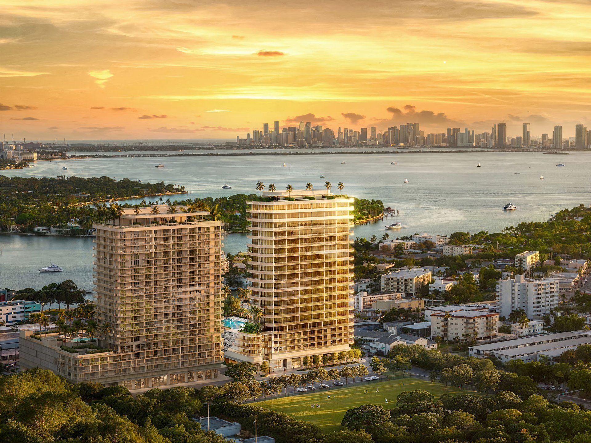 72 Carlyle waterfront residences with twin towers, Biscayne Bay, and the Miami skyline at sunset.