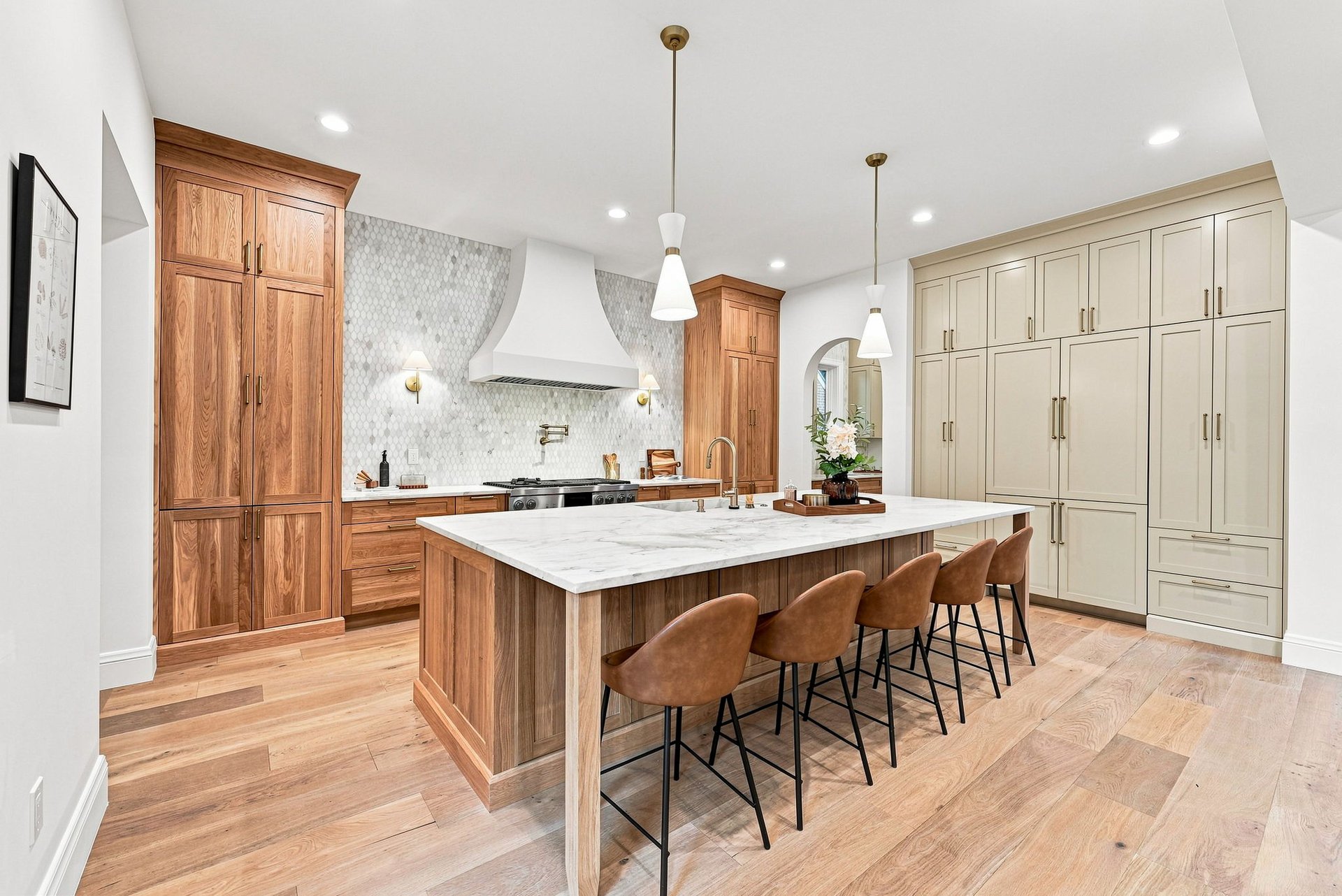 Kitchen with a marble island, walnut cabinetry, cream built-ins, and brown bar stools.