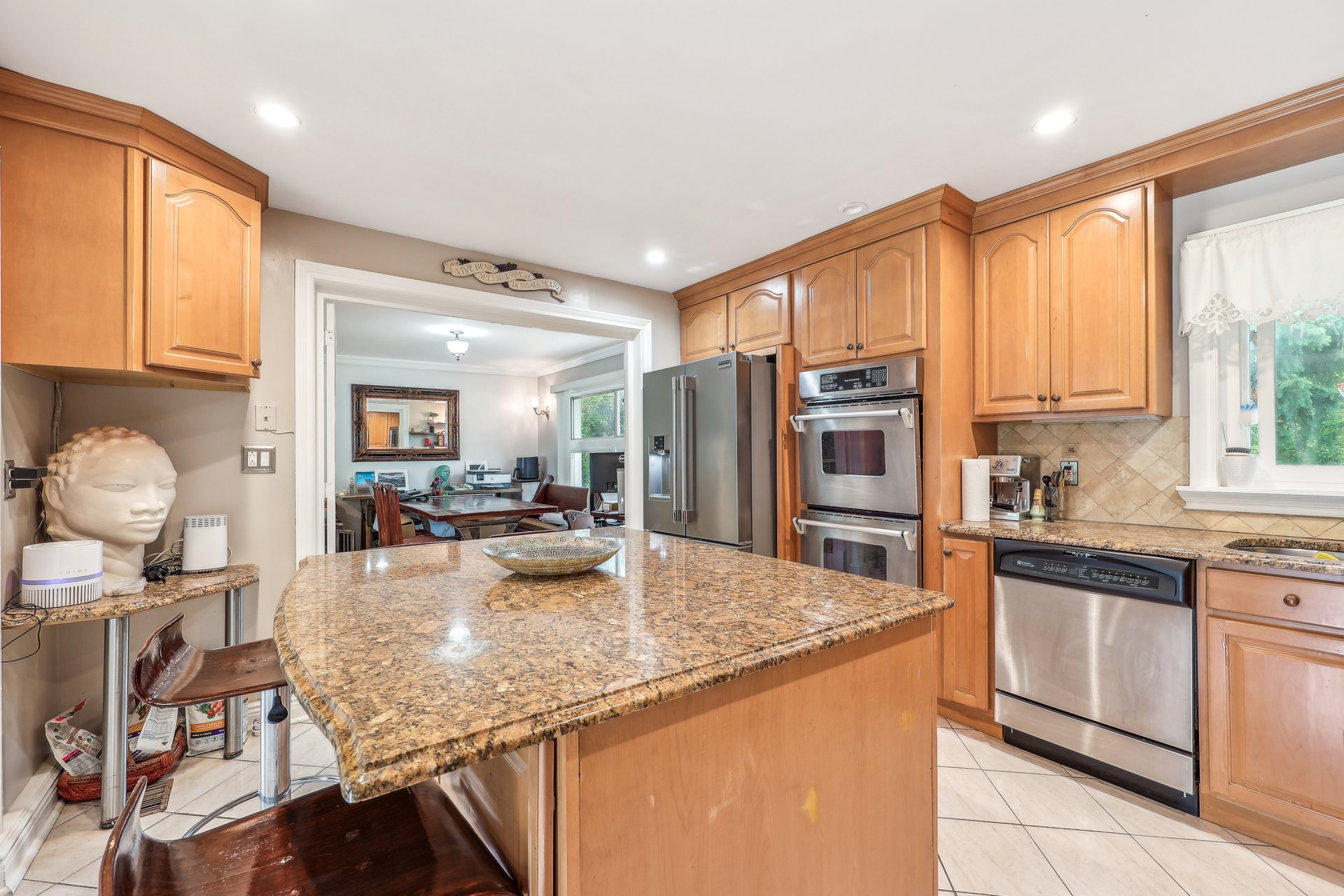 Kitchen with a large granite island, warm wood cabinets, and stainless steel appliances.