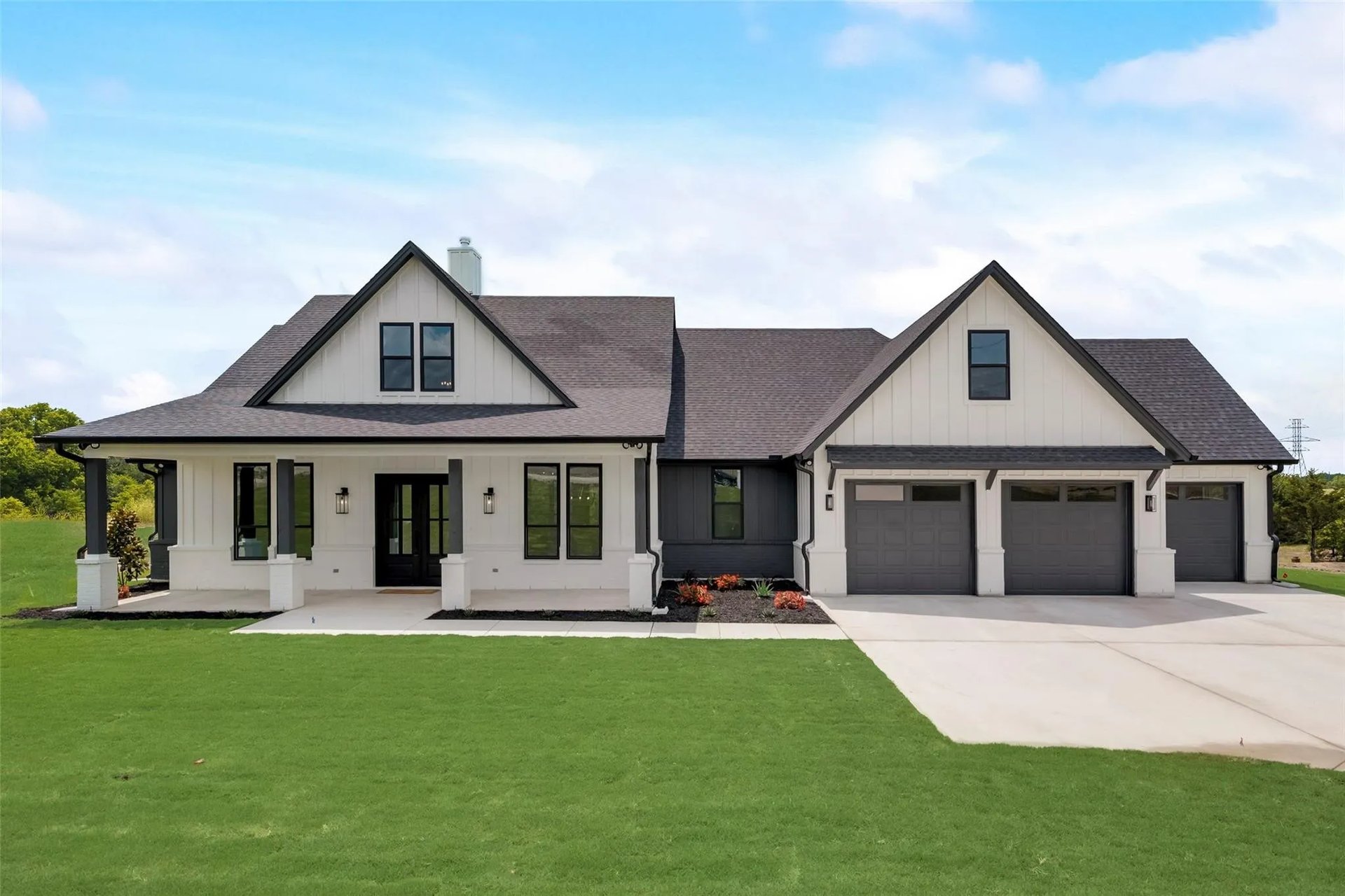 White farmhouse with twin gables, a covered porch, and a three-car garage.