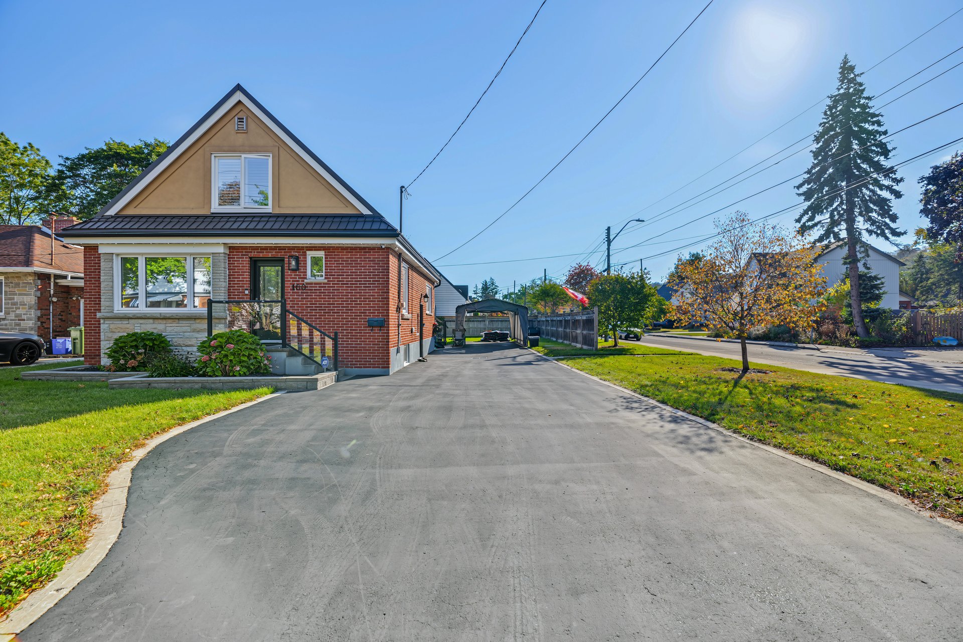 Red-brick house with a steep front gable beside a wide paved driveway.