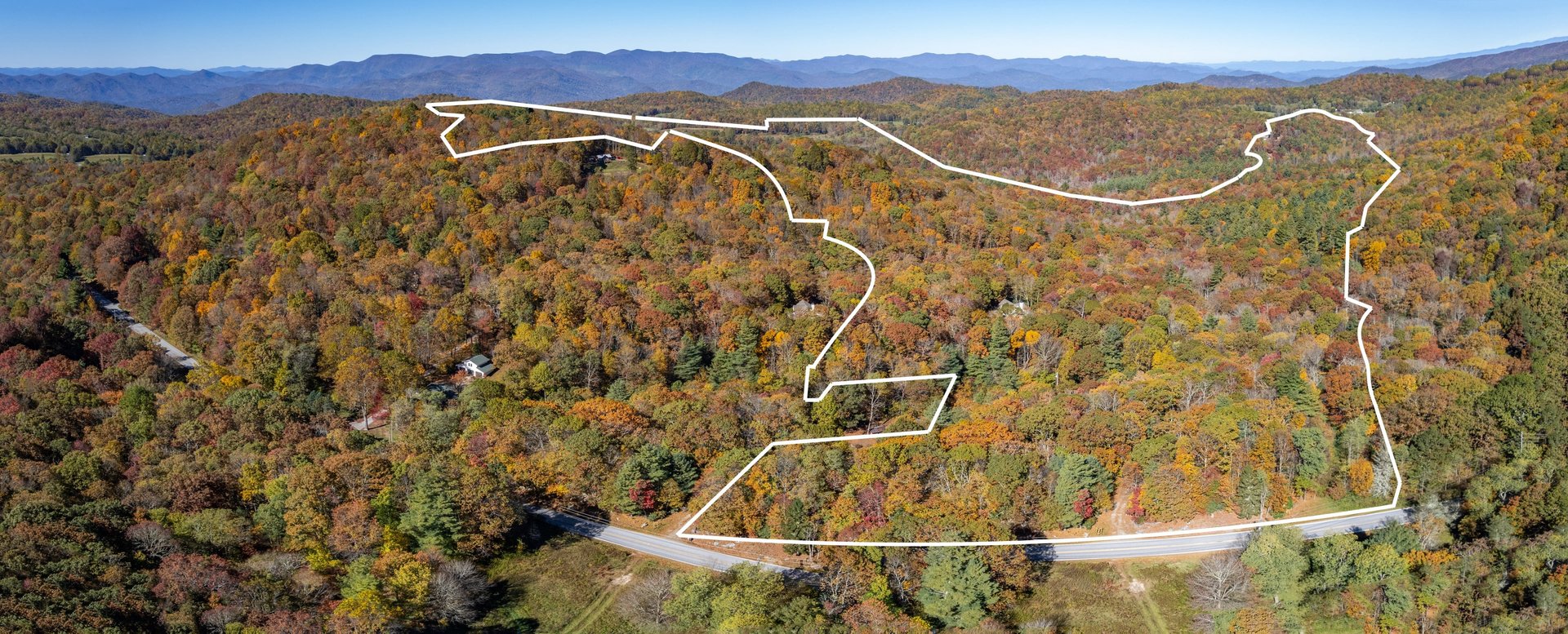 Aerial view of 211.67 wooded acres in fall color with the property boundary outlined at 6507 Dillard Road, Scaly Mountain NC