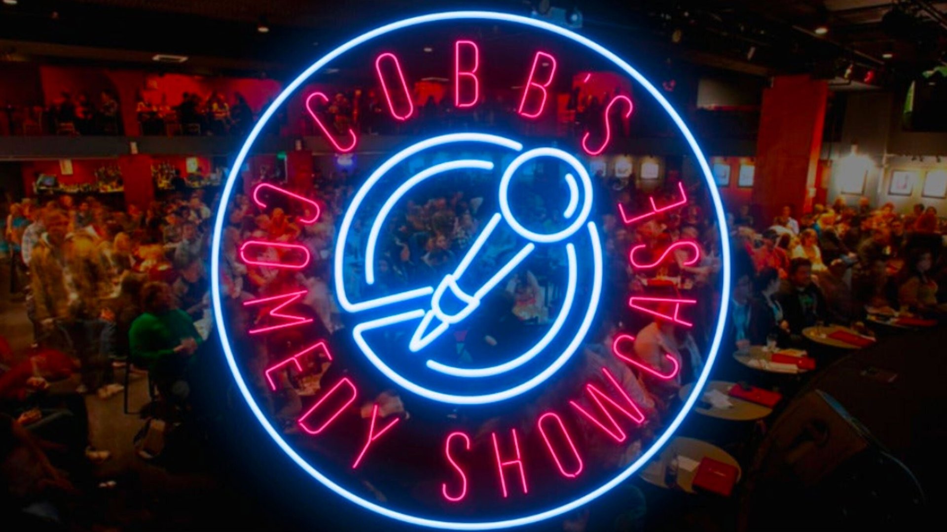 The exterior of Cobb's Comedy Club in San Francisco, featuring a brightly lit marquee displaying the club's name and upcoming performances. The entrance is bustling with people, set against an urban backdrop with streetlights illuminating the area at night.