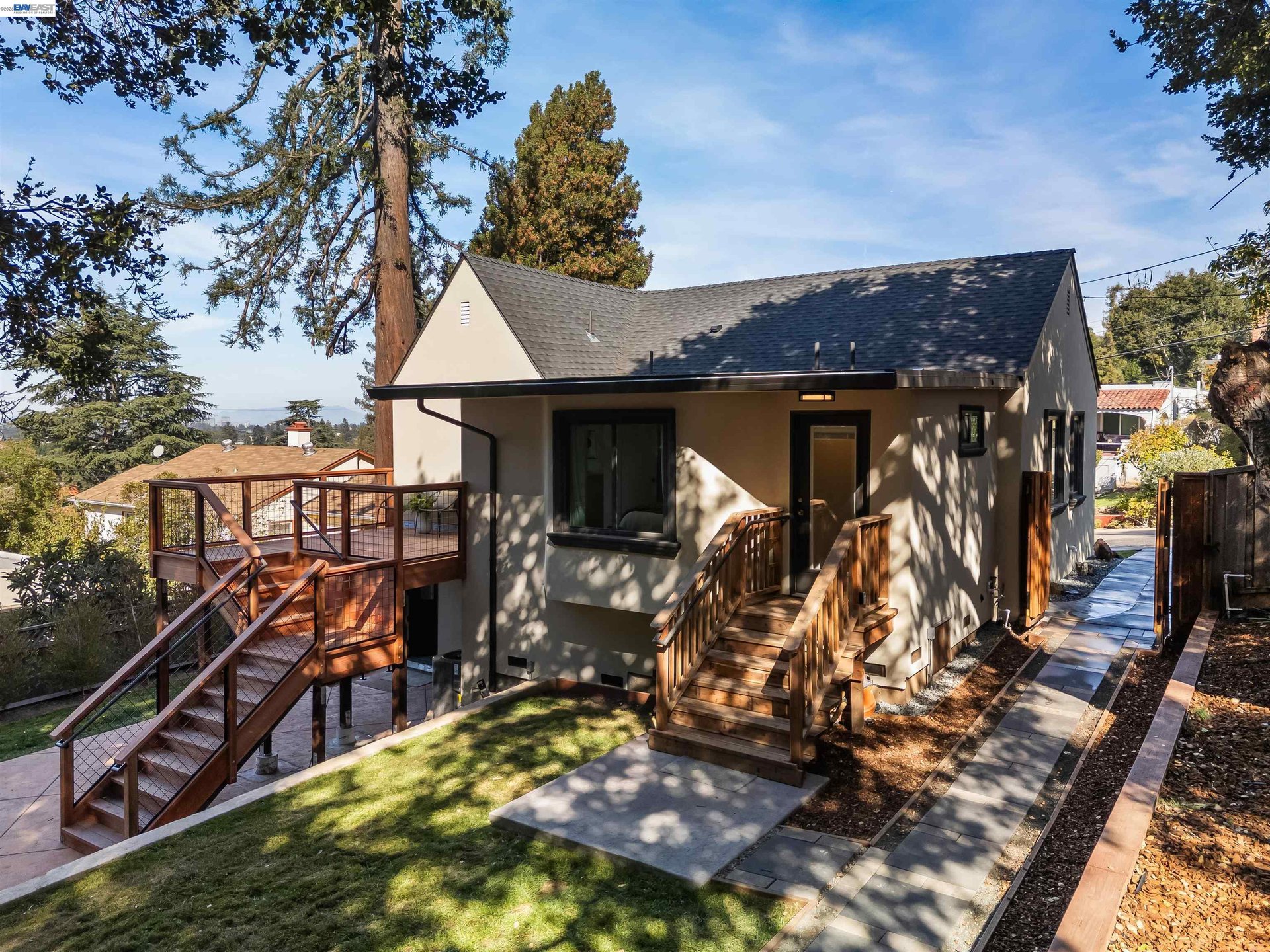 Oakland home with elevated wooden decks, stairs, and a landscaped yard beneath mature trees.