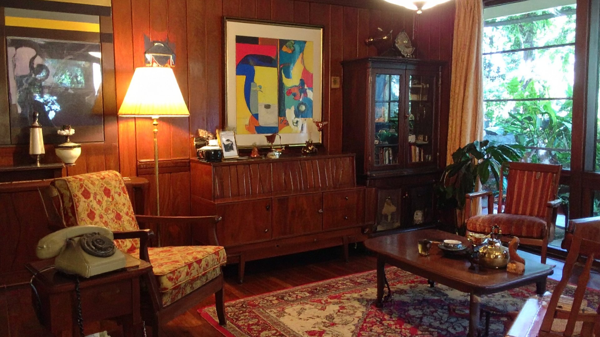 Maximalist room with wood paneling, vintage furniture, colorful artwork, and tropical views - The Edit Real Estate Miami design