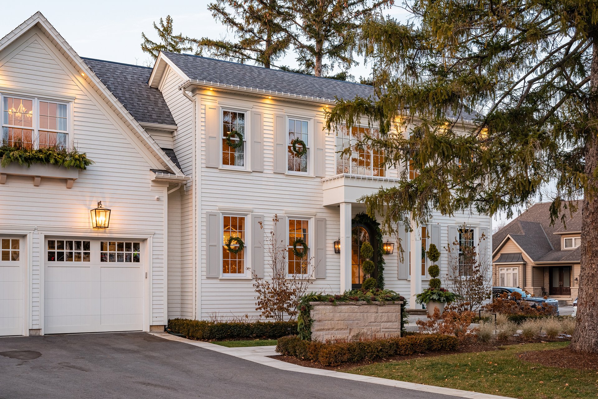 Exterior of an Oakville custom home with Georgian-inspired architecture, holiday wreaths, and greenery accents.