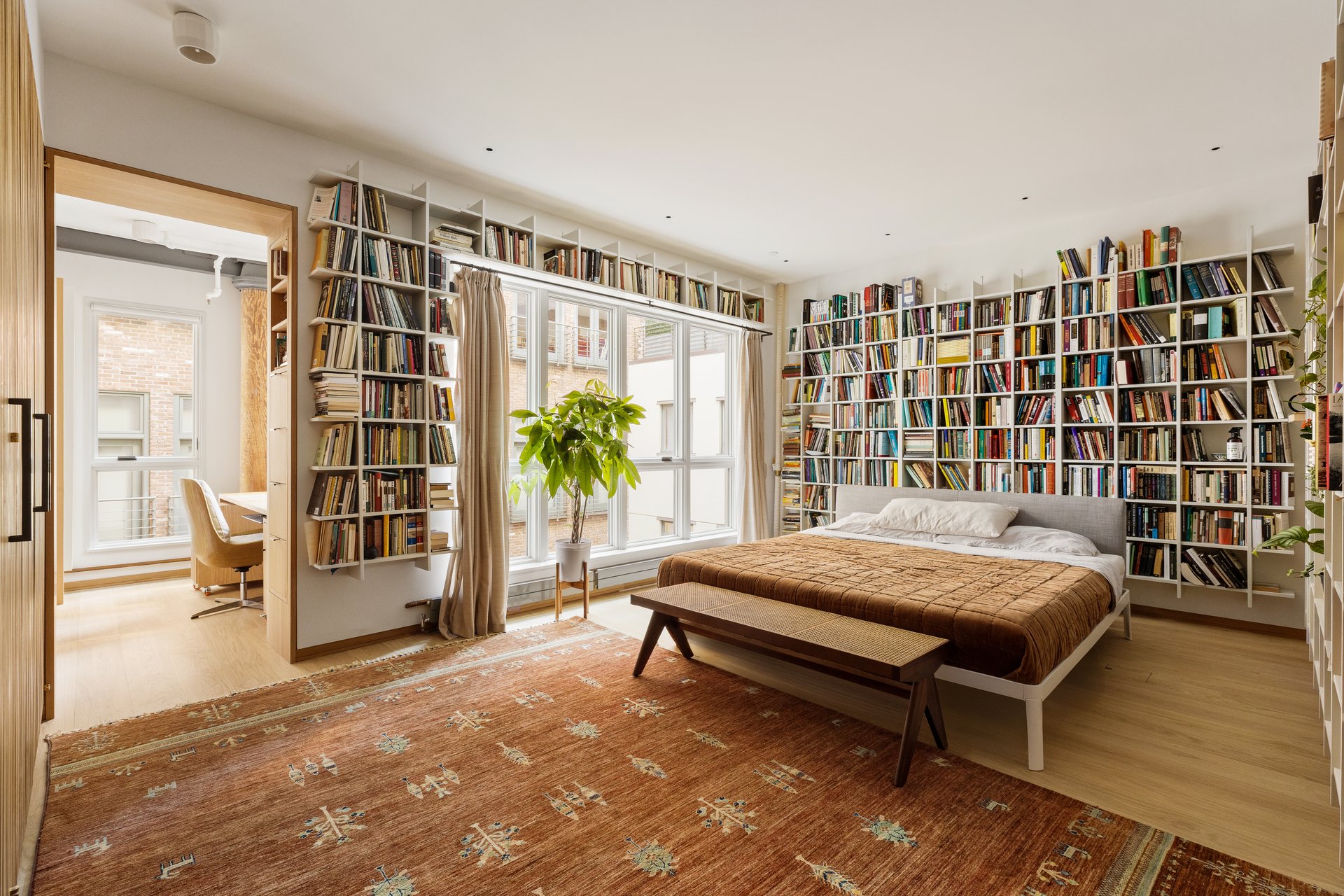 Primary bedroom at 50 Wooster Street 4NR, with wraparound bookshelves and glass doors.