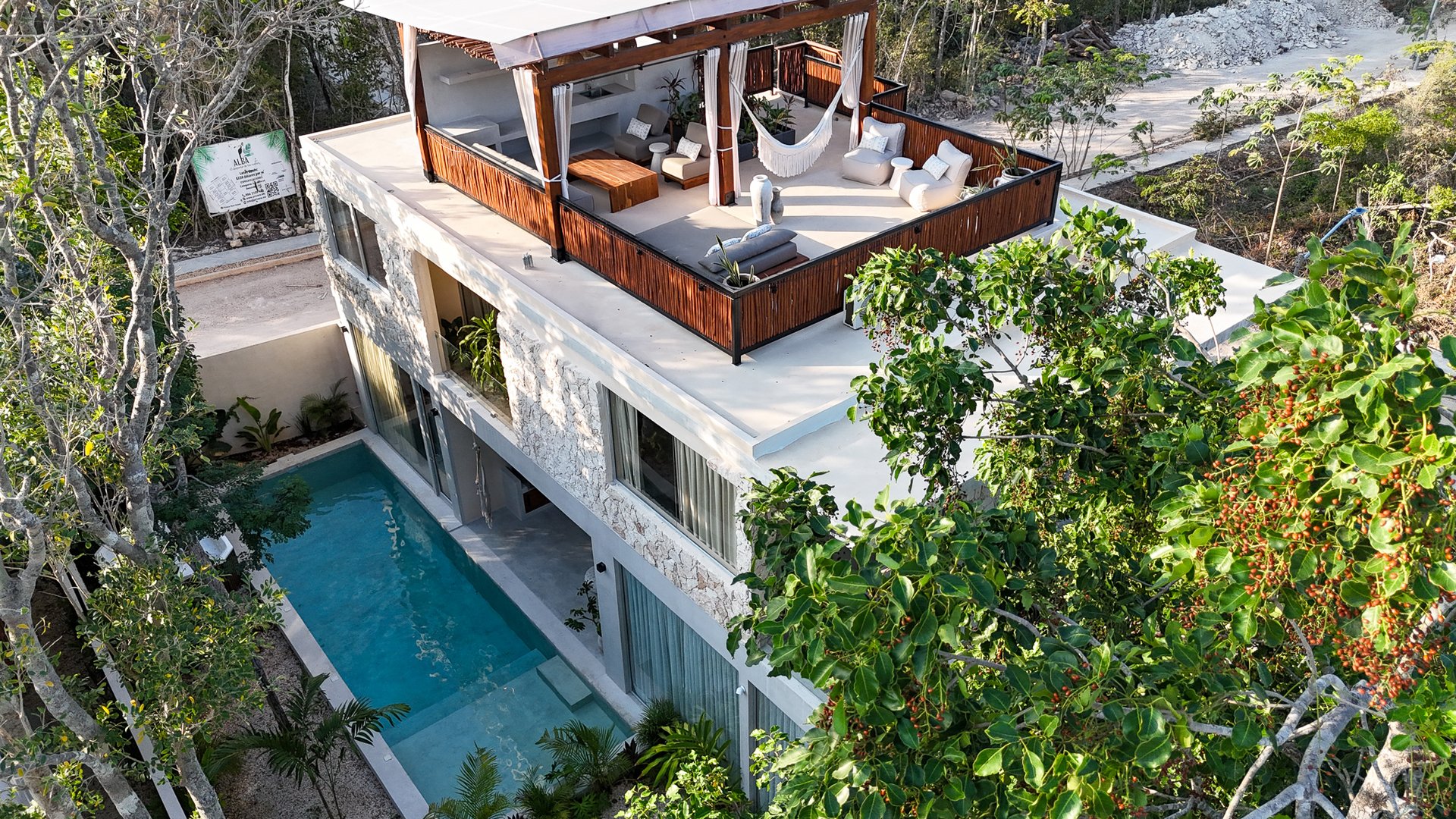 Casa Mazuri villa with a rooftop lounge and long swimming pool, surrounded by tropical trees.